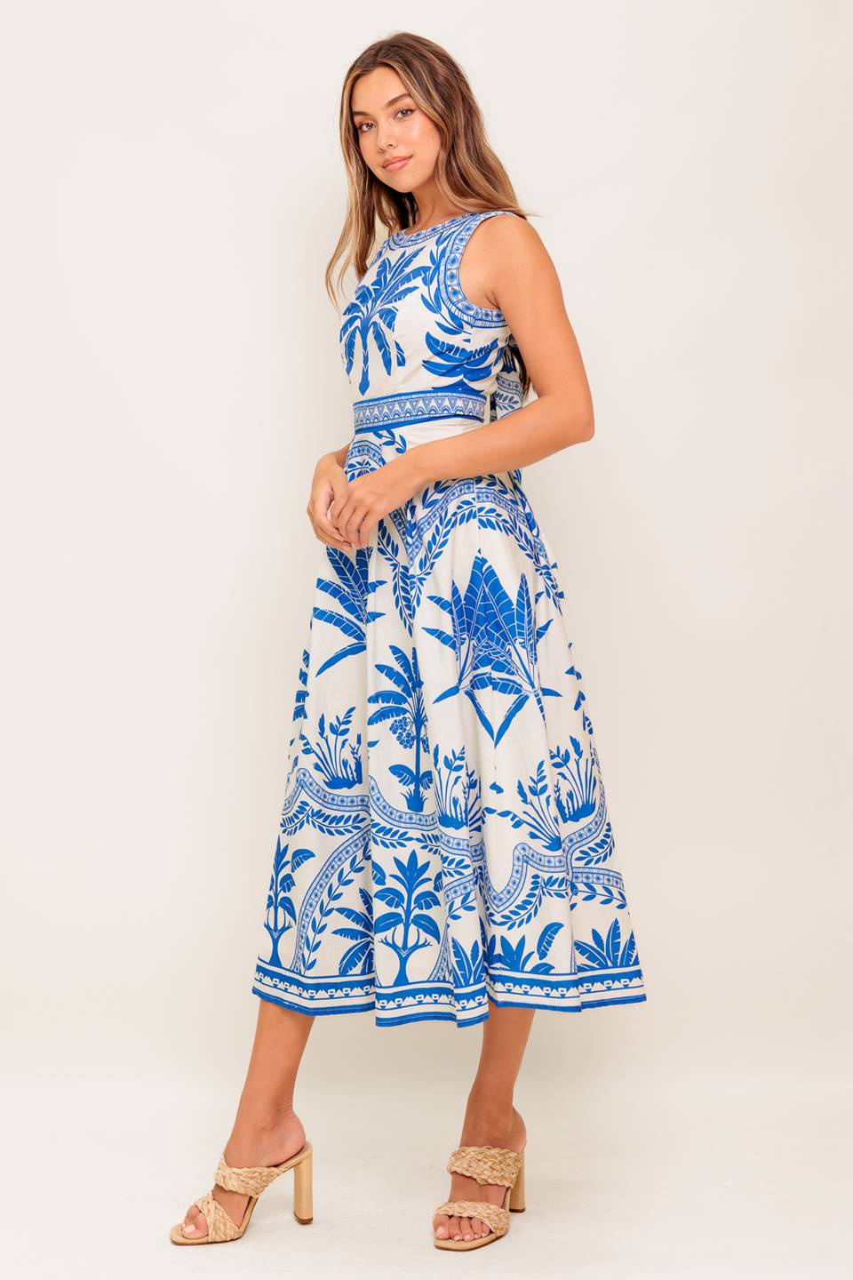 A printed woven midi dress featuring round neckline, sleeveless, circle skirt and tie back with zipper closure