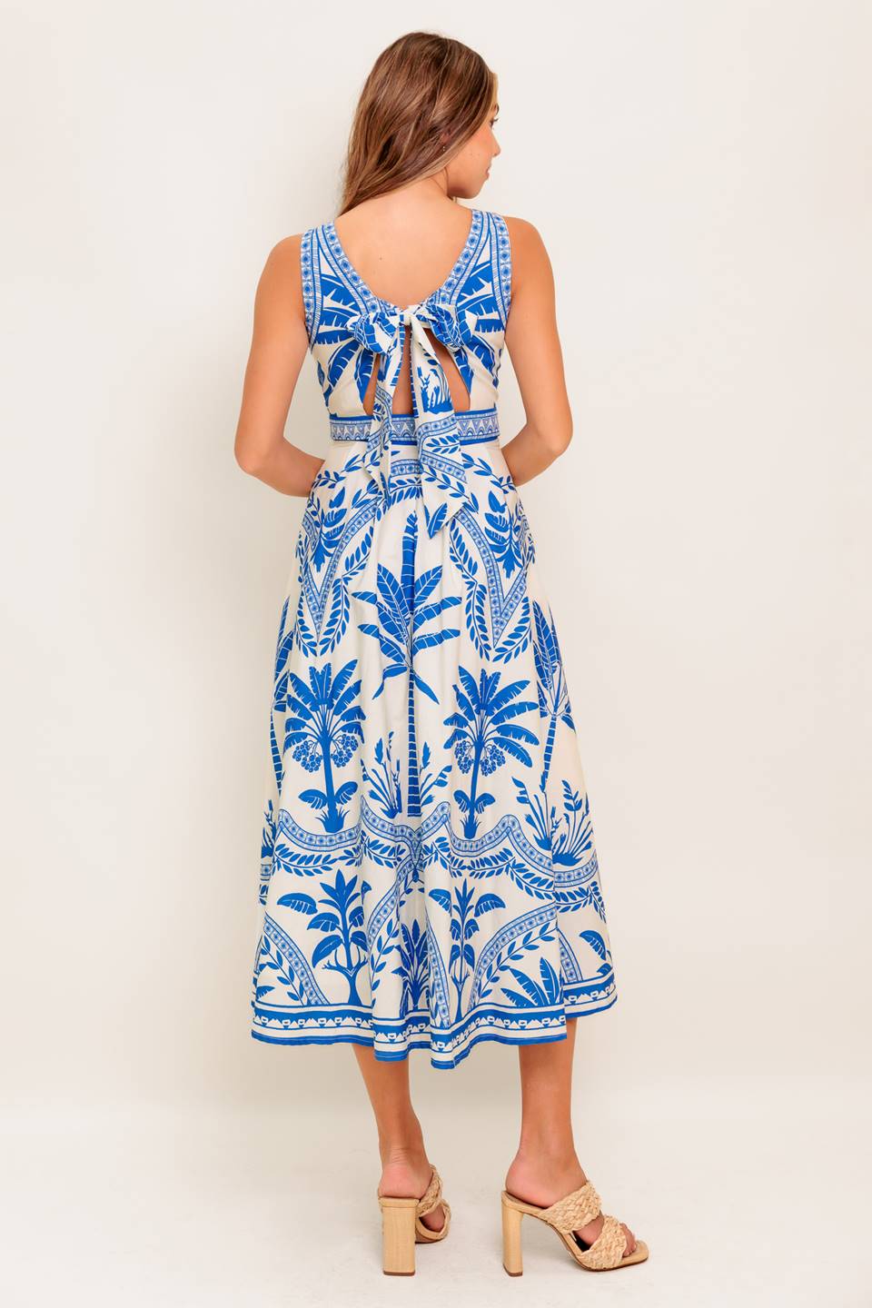 A printed woven midi dress featuring round neckline, sleeveless, circle skirt and tie back with zipper closure