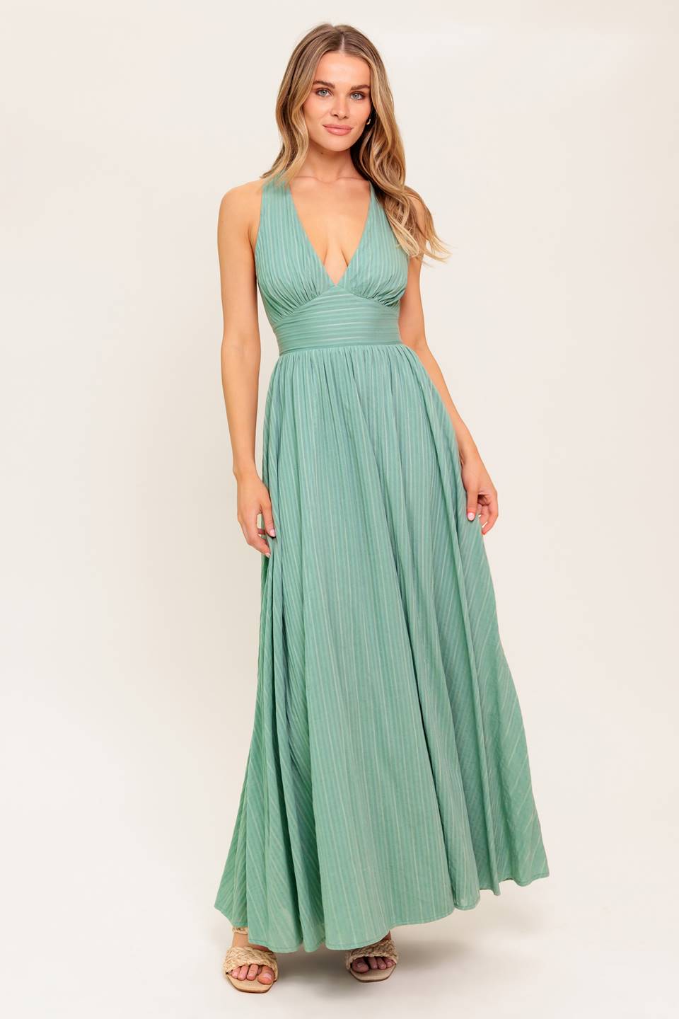 A textured woven maxi dress featuring V neckline, sleeveless, waist yoke, full skirt and bare back with cross back.