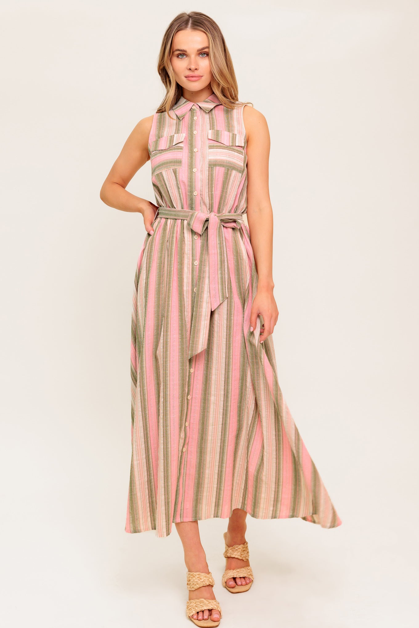 A striped woven midi dress featuring collar, button down, pockets, elasticized waist, self sash and full skirt.