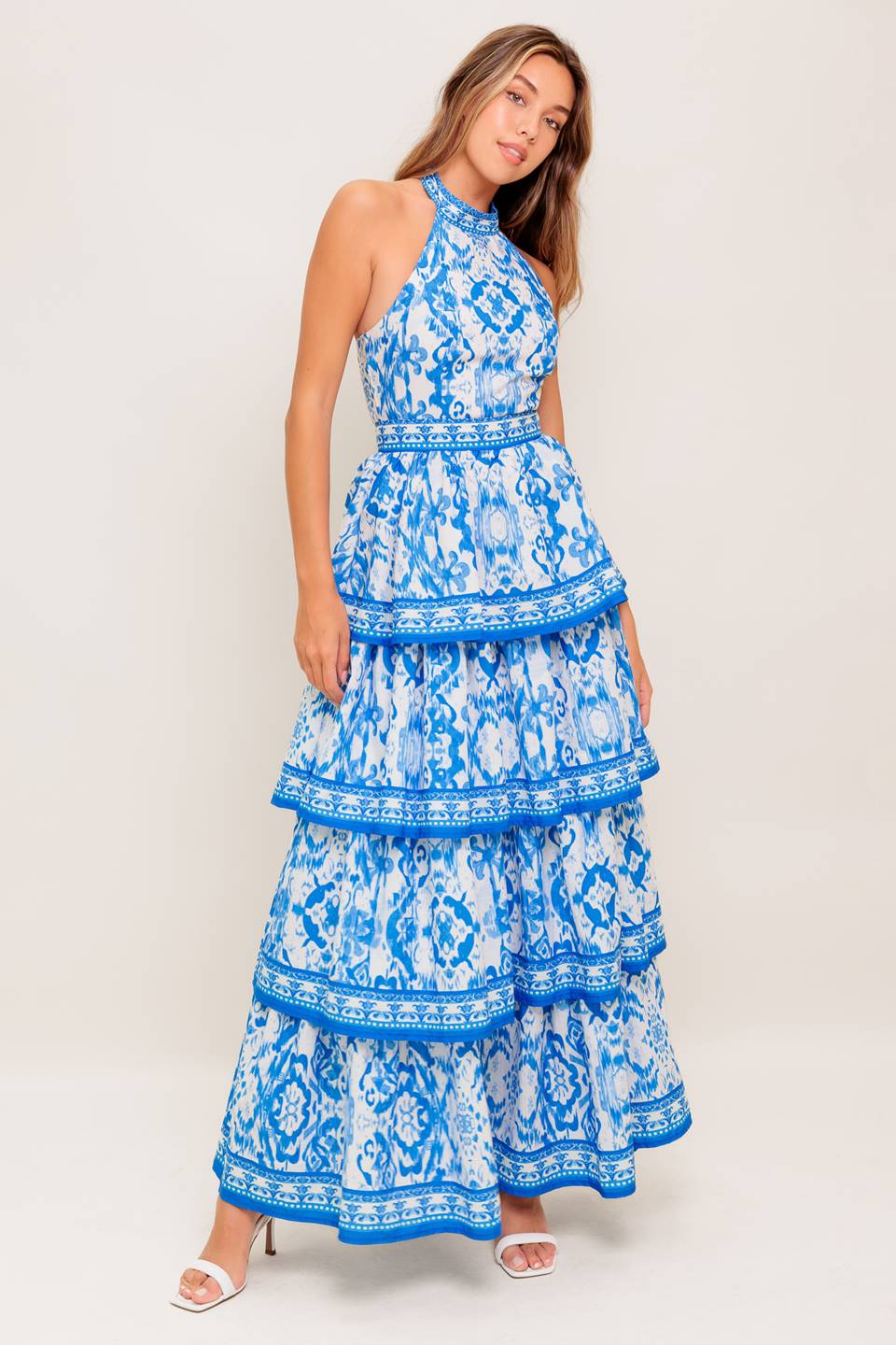 A printed woven maxi dress featuring halter neckline, sleeveless, layered skirt and back zipper closure