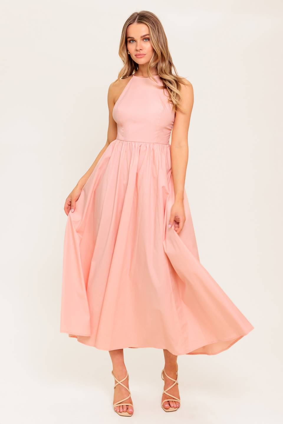 A solid woven midi dress featuring halter neckline, full skirt, bare back with cross straps and zipper closure.