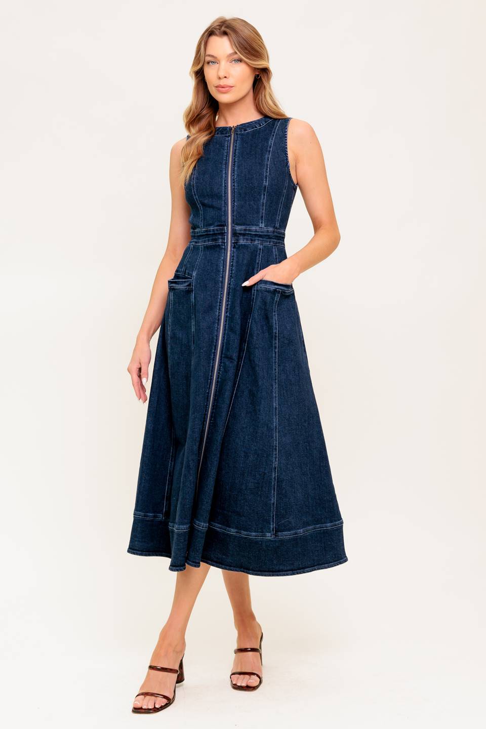 A washed denim midi dress featuring round neckline, sleeveless, front zipper closure, side pocket and circle skirt.