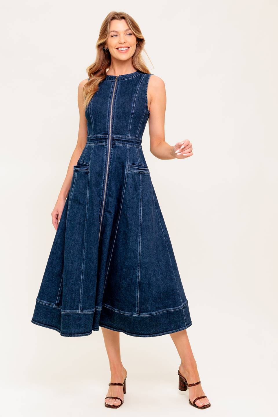 A washed denim midi dress featuring round neckline, sleeveless, front zipper closure, side pocket and circle skirt.