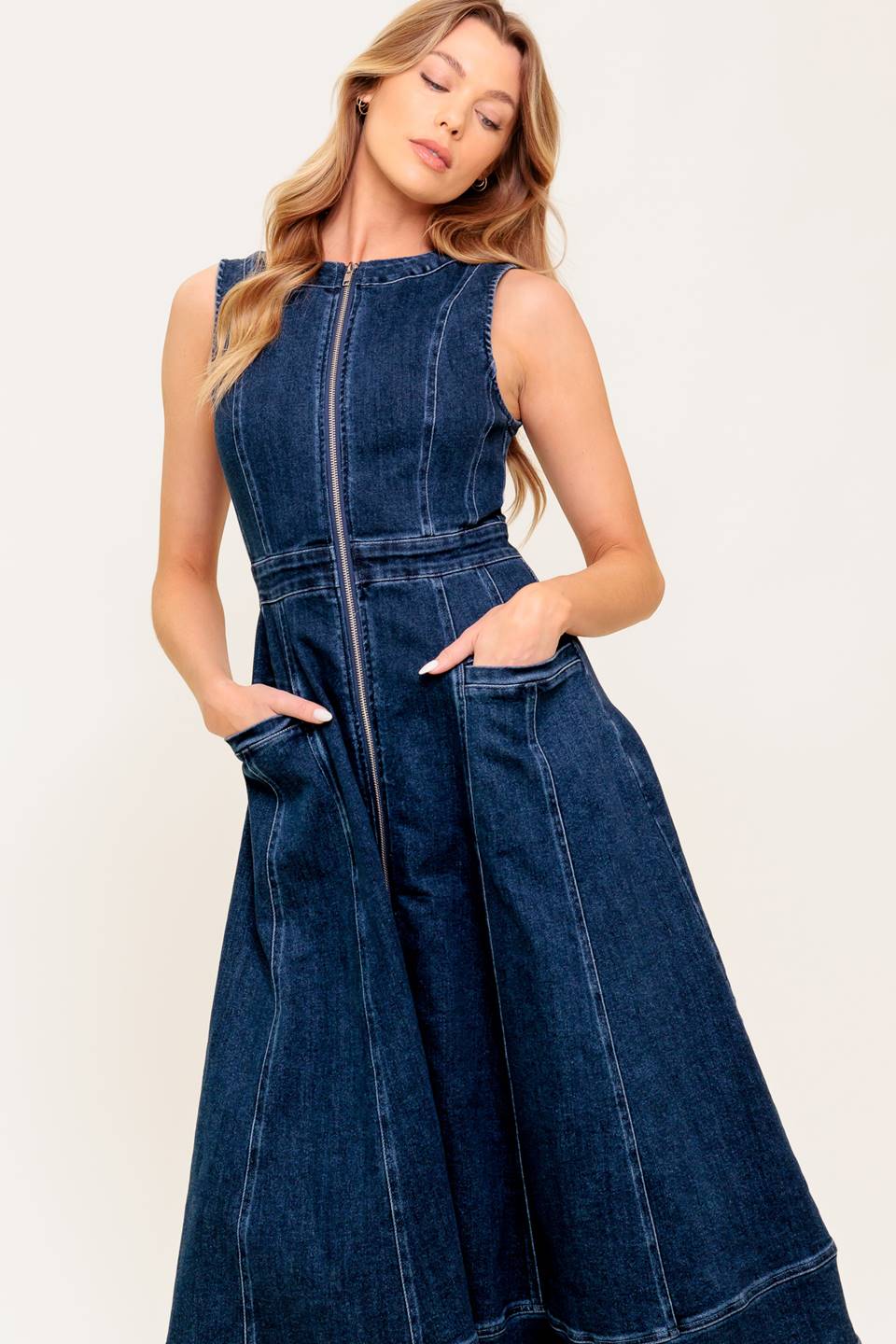 A washed denim midi dress featuring round neckline, sleeveless, front zipper closure, side pocket and circle skirt.