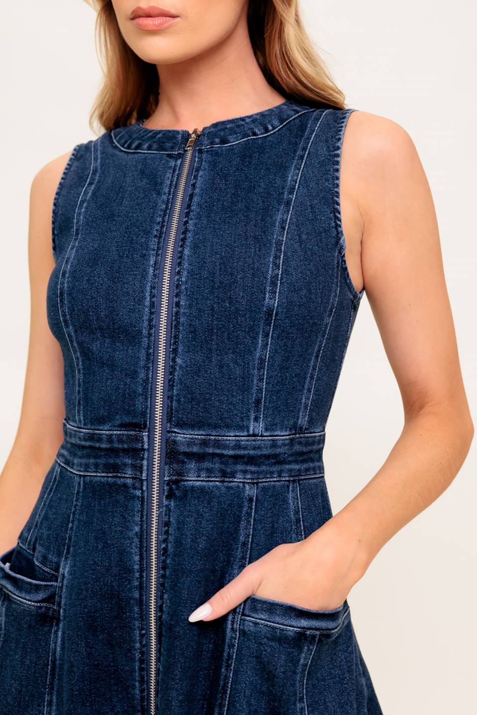 A washed denim midi dress featuring round neckline, sleeveless, front zipper closure, side pocket and circle skirt.
