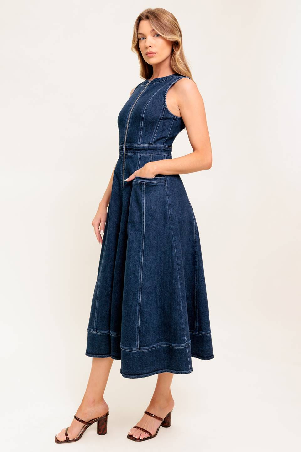 A washed denim midi dress featuring round neckline, sleeveless, front zipper closure, side pocket and circle skirt.