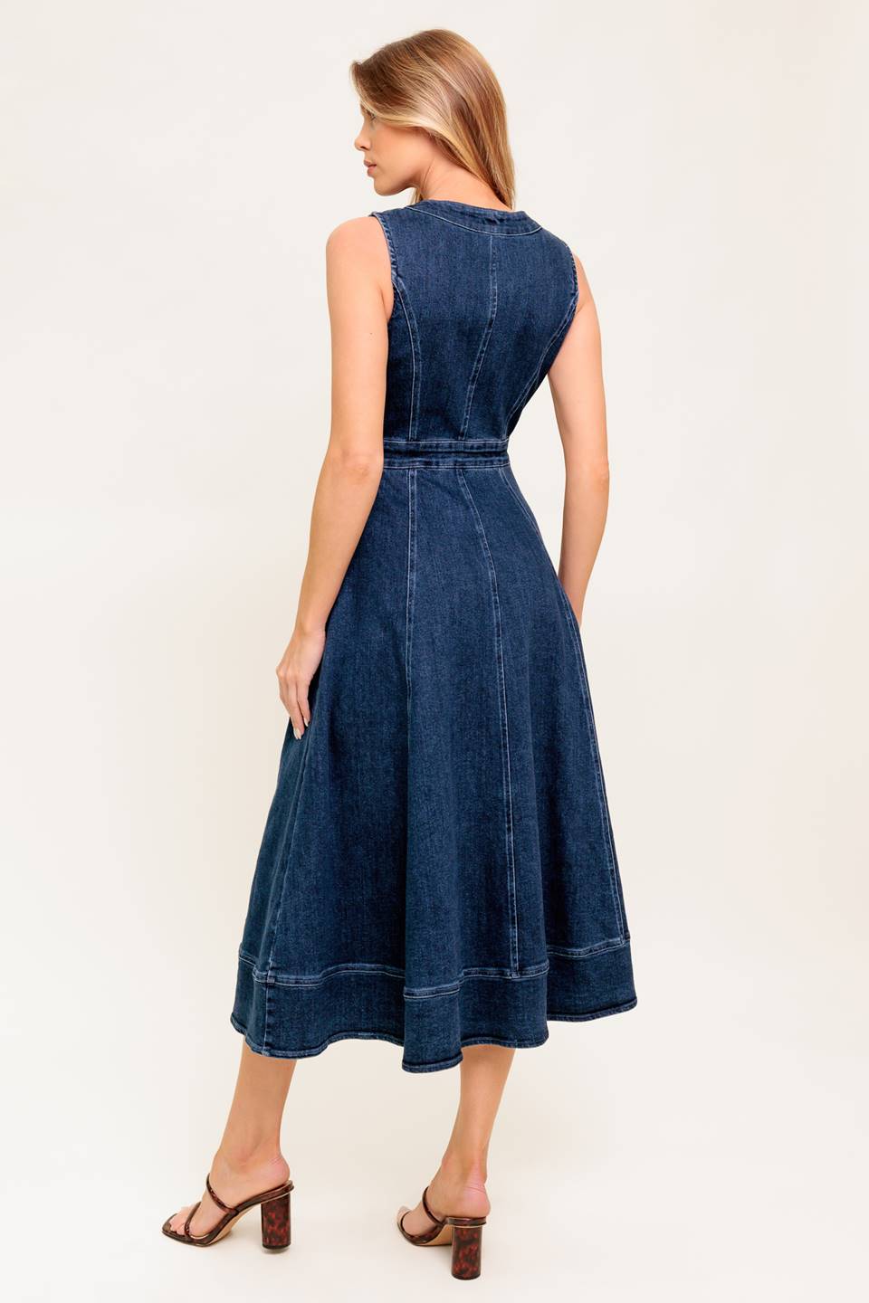 A washed denim midi dress featuring round neckline, sleeveless, front zipper closure, side pocket and circle skirt.
