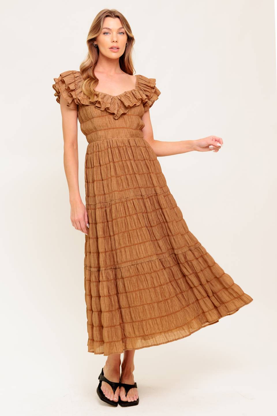 A textured woven midi dress featuring ruffles neckline, short ruffle sleeve, tiered skirt and smocked back bodice.