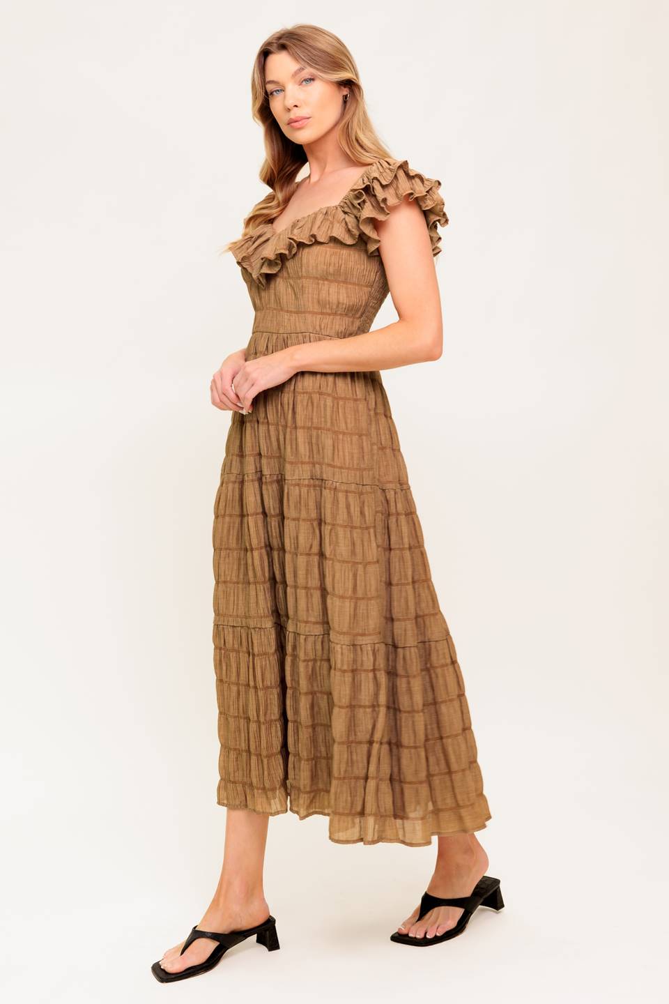 A textured woven midi dress featuring ruffles neckline, short ruffle sleeve, tiered skirt and smocked back bodice.