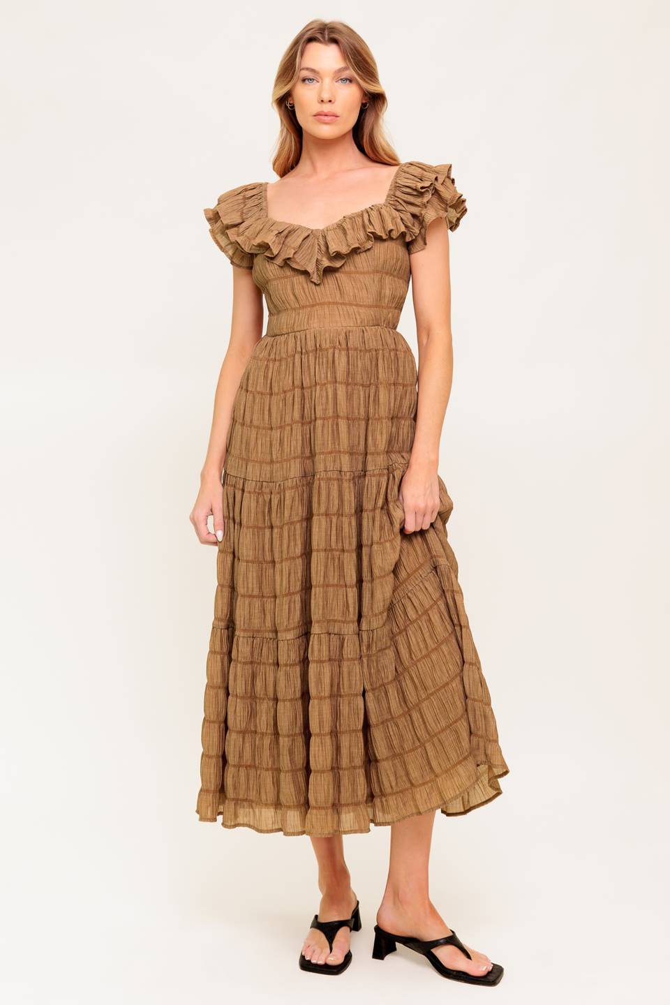 A textured woven midi dress featuring ruffles neckline, short ruffle sleeve, tiered skirt and smocked back bodice.