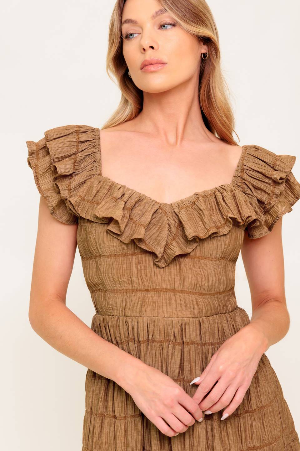 A textured woven midi dress featuring ruffles neckline, short ruffle sleeve, tiered skirt and smocked back bodice.
