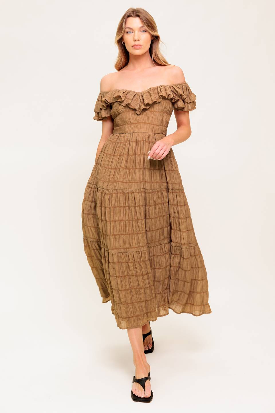A textured woven midi dress featuring ruffles neckline, short ruffle sleeve, tiered skirt and smocked back bodice.