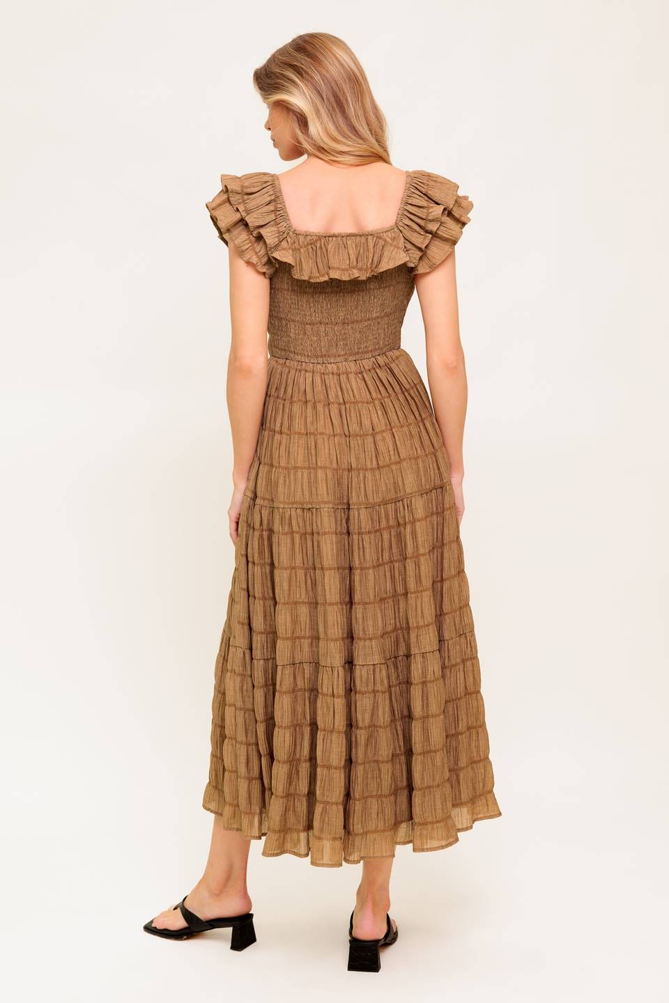 A textured woven midi dress featuring ruffles neckline, short ruffle sleeve, tiered skirt and smocked back bodice.