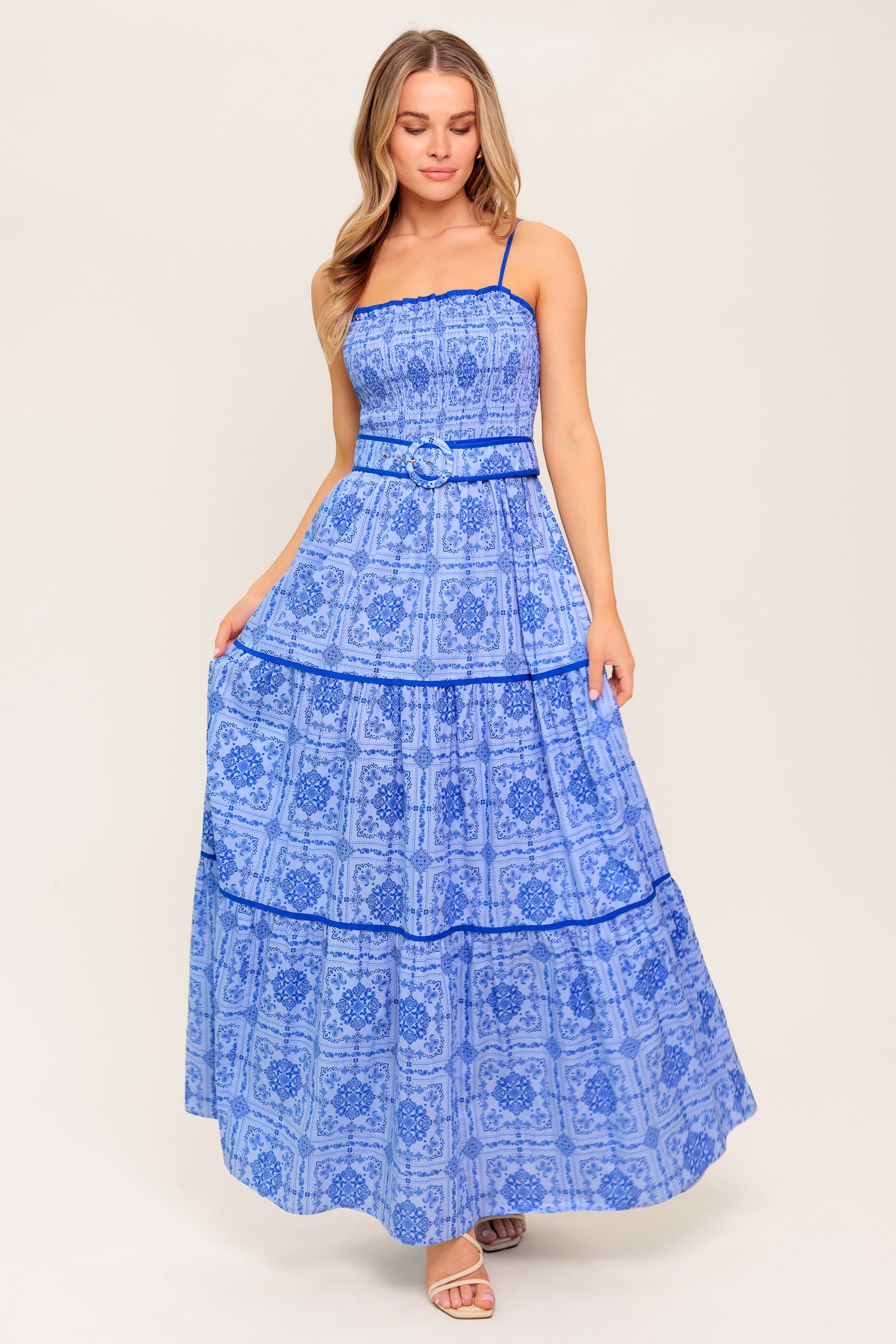 A printed woven maxi dress featuring straight neckline, straps, smocked bodice, self belt and tiered skirt.