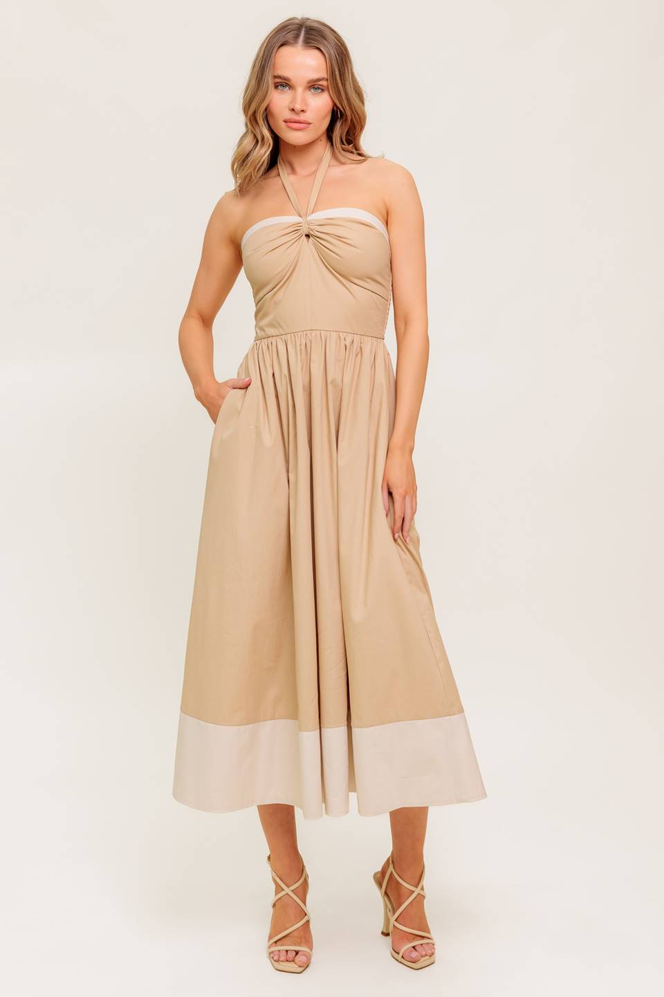 A solid woven midi dress featuring sweetheart neckline with gathered front, halter tie, full skirt and smocked back bodice.