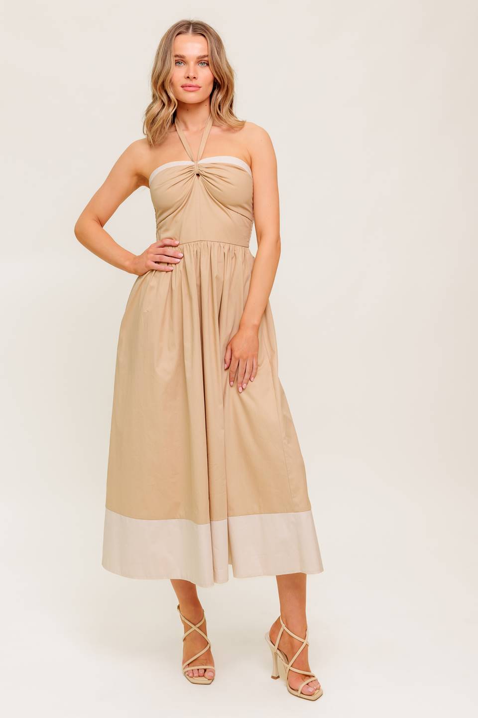 A solid woven midi dress featuring sweetheart neckline with gathered front, halter tie, full skirt and smocked back bodice.