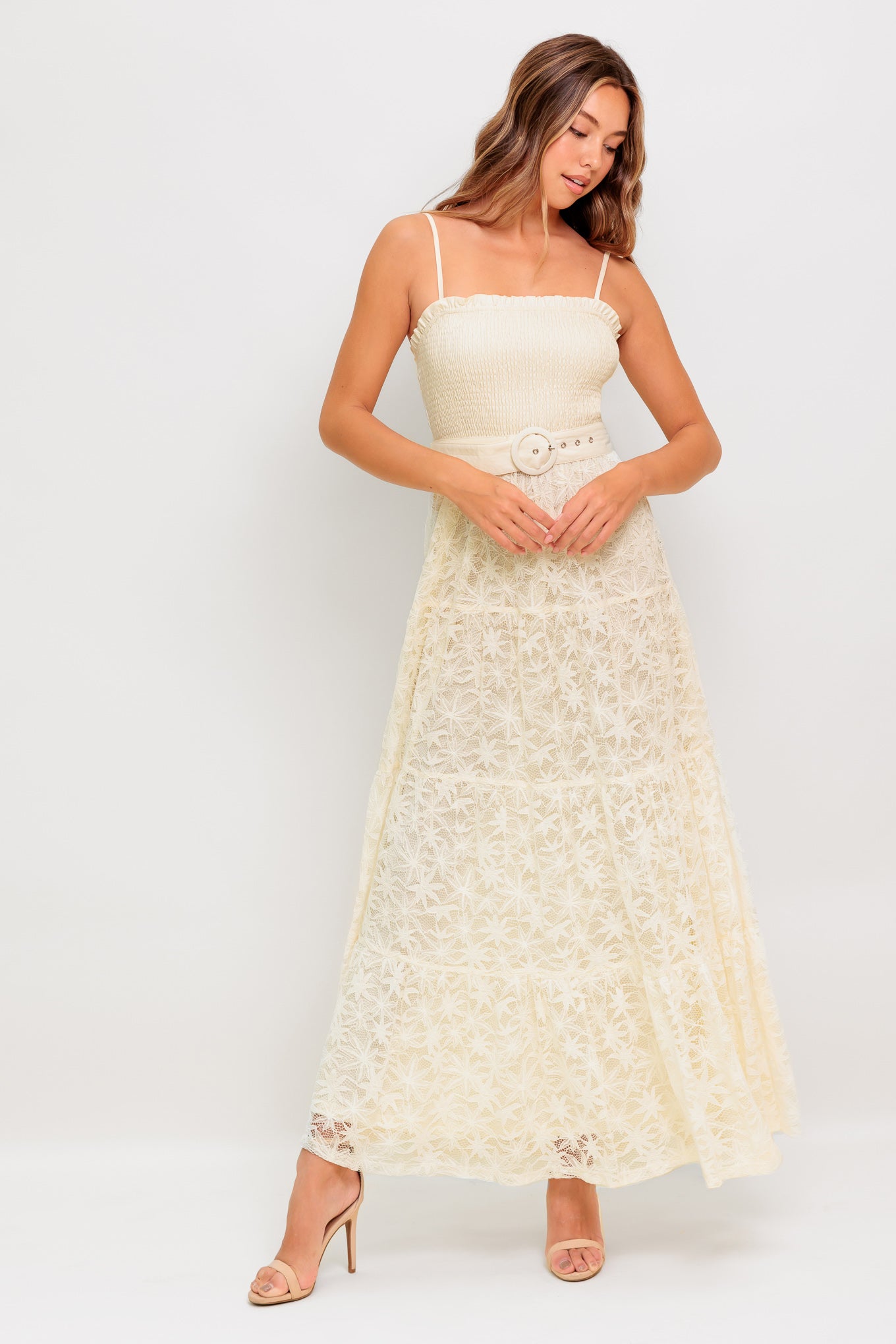 A woven lace ankle length dress featuring straight neckline with ruffled edge, smocked bodice, straps, self belt and tiered skirt