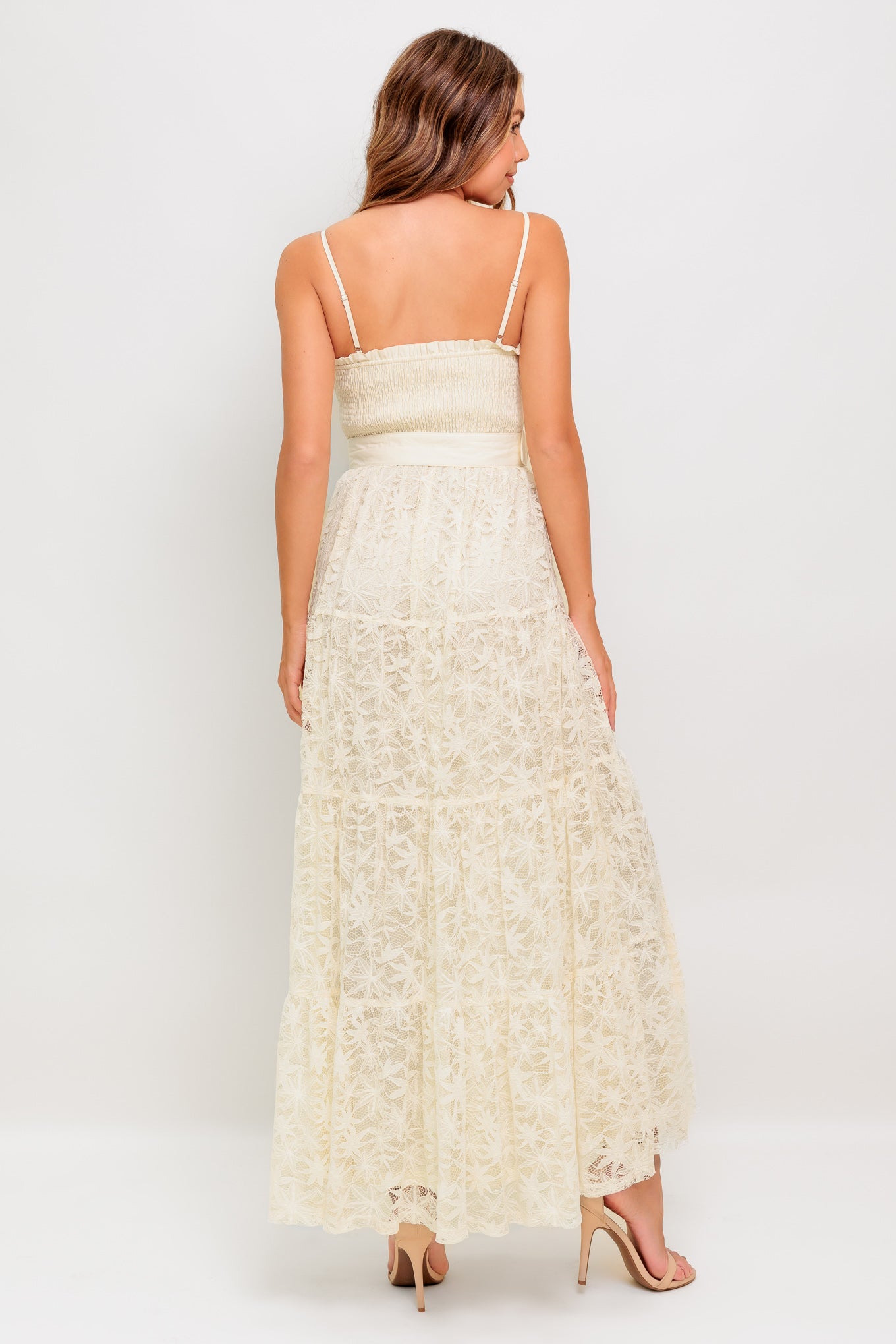 A woven lace ankle length dress featuring straight neckline with ruffled edge, smocked bodice, straps, self belt and tiered skirt