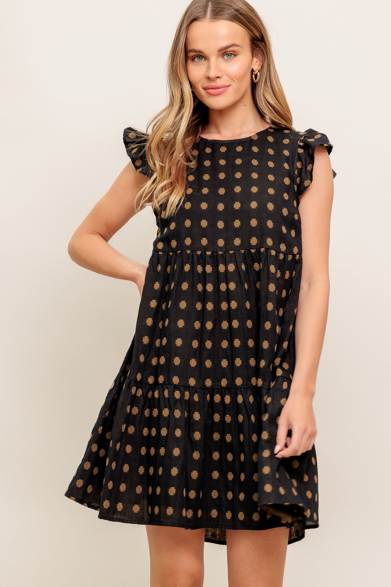 A textured woven mini dress featuring round neckline, ruffled sleeve, tiered body and back neck button closure