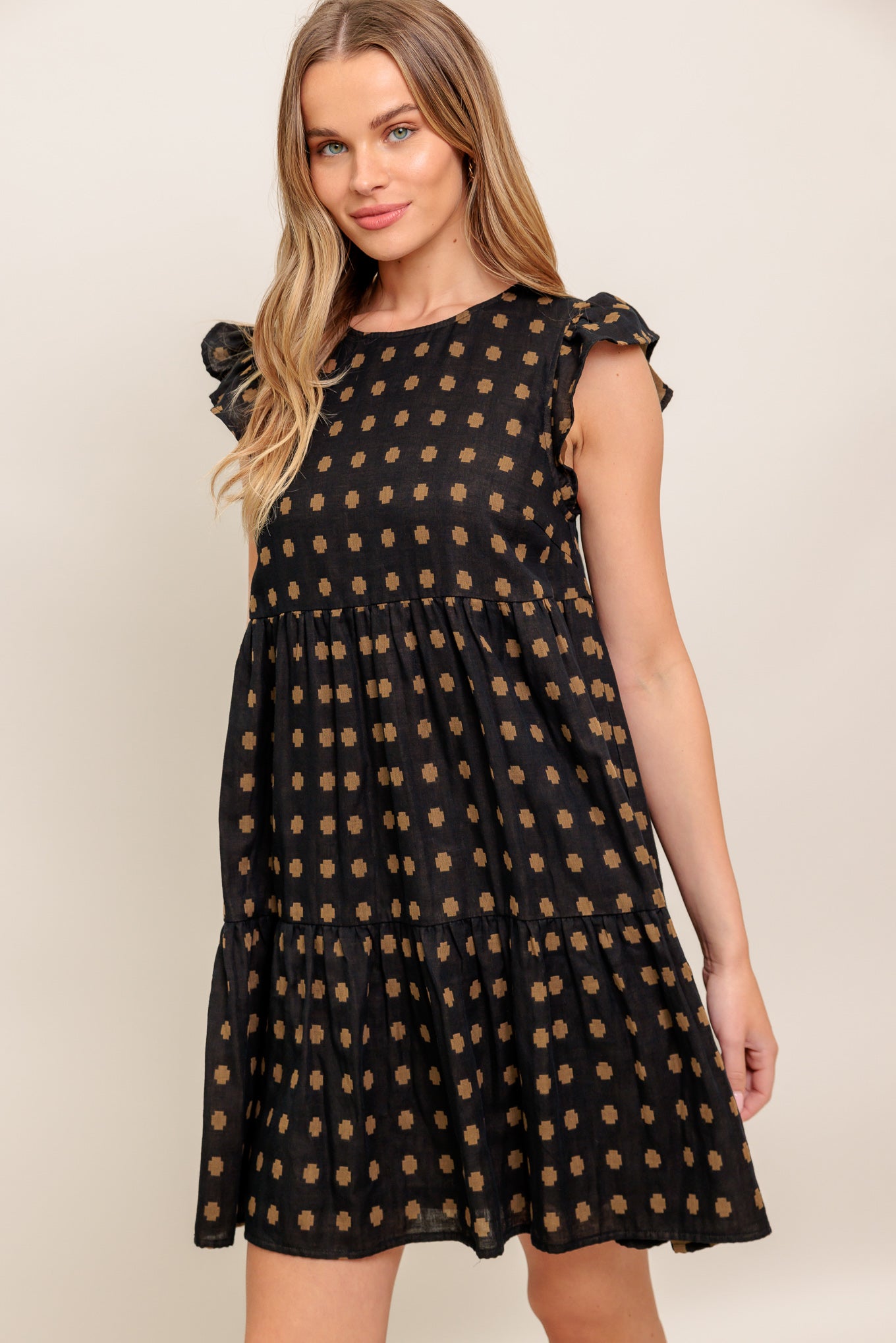 A textured woven mini dress featuring round neckline, ruffled sleeve, tiered body and back neck button closure