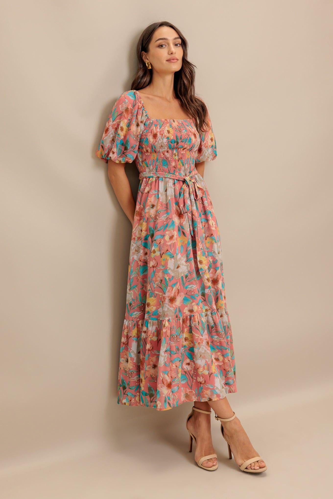 A printed woven midi dress featuring square neckline, short puff sleeve, smocked bodice, self sash tie and ruffled hemline