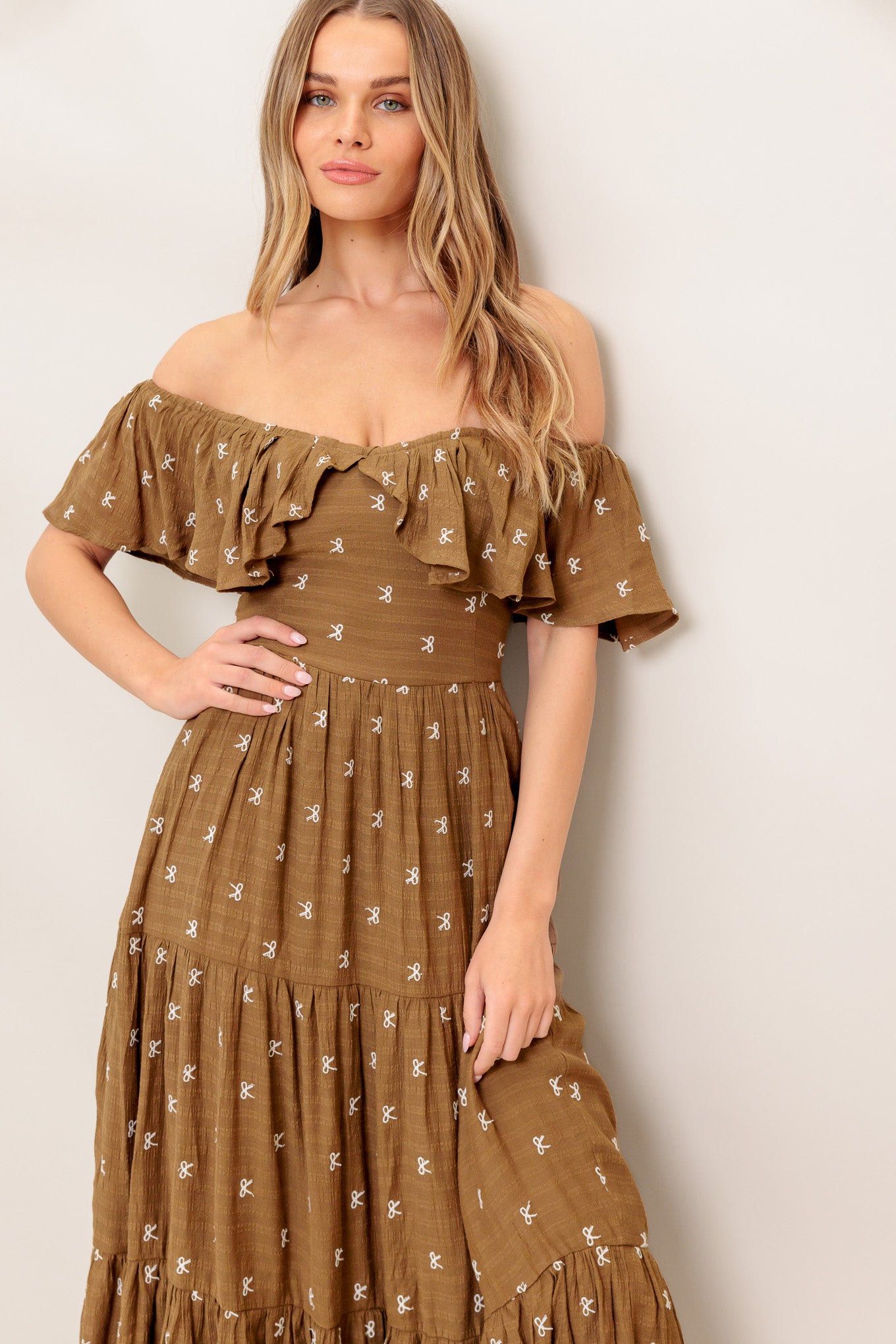 A textured embroidered woven midi dress featuring off shoulder neckline with flounce, tiered skirt and smocked back bodice
