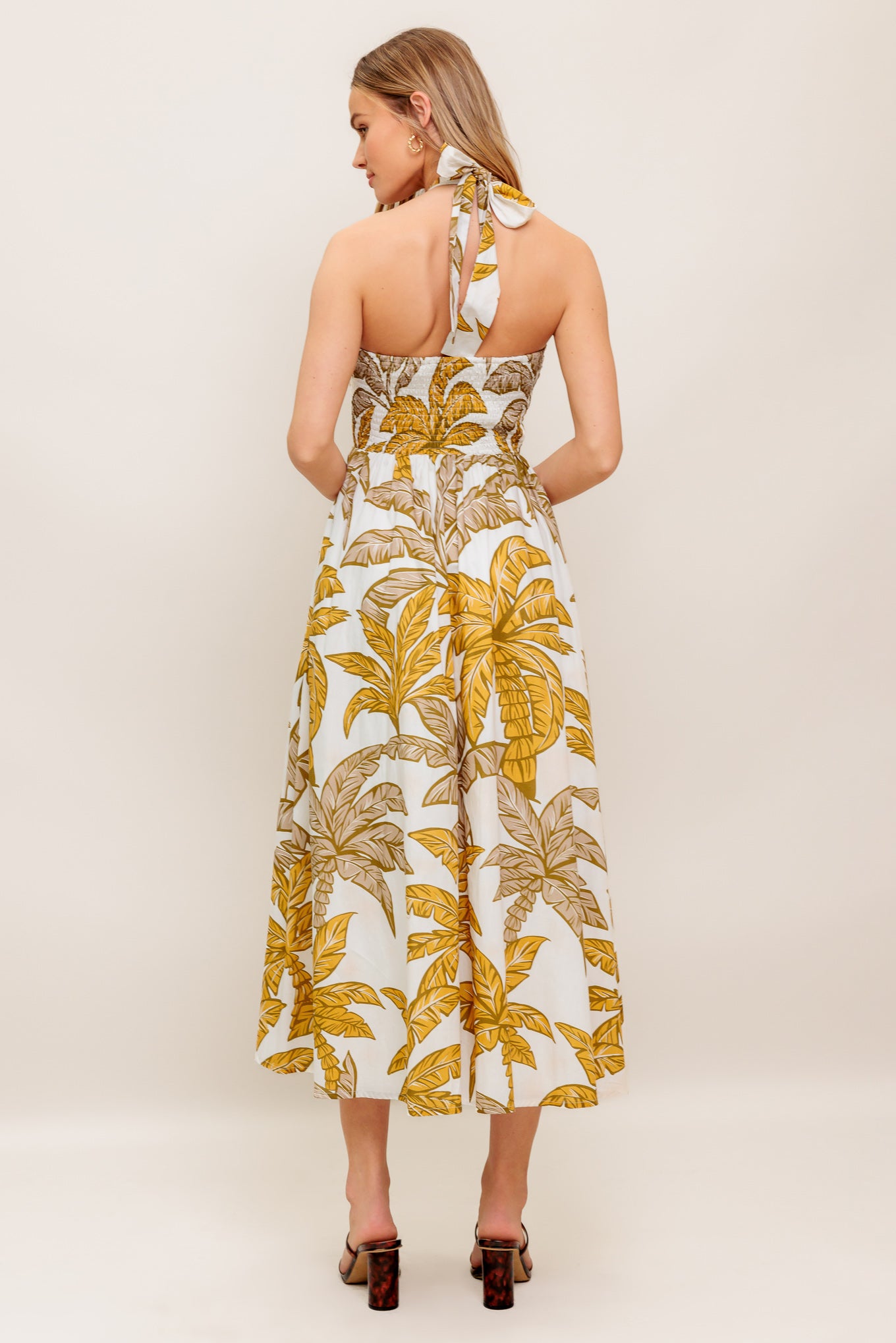 A printed woven midi dress featuring halter neckline with back neck tie, full skirt and smocked back bodice