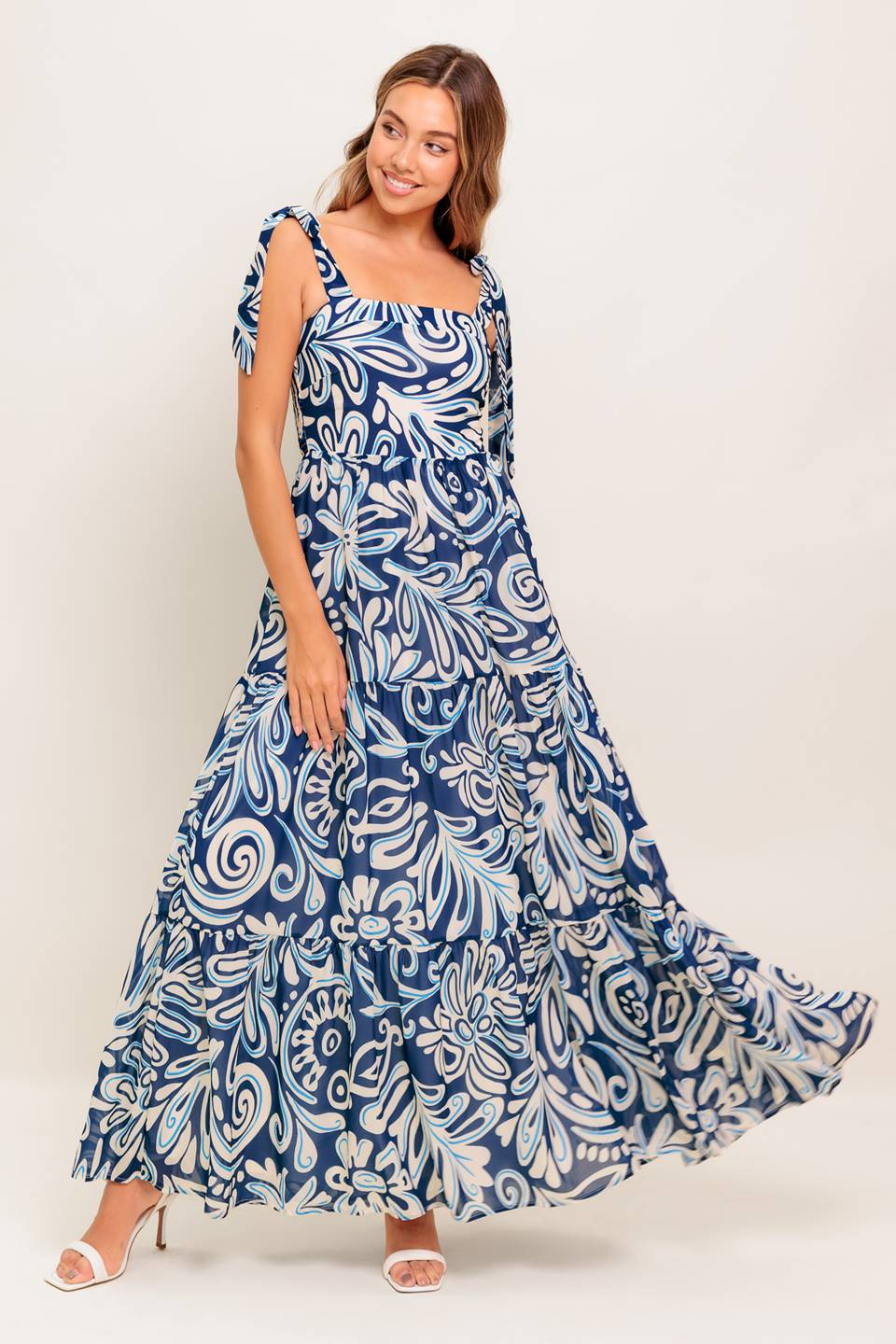 A printed woven maxi dress featuring straight neckline, shoulder ties, tiered skirt and smocked back bodice
