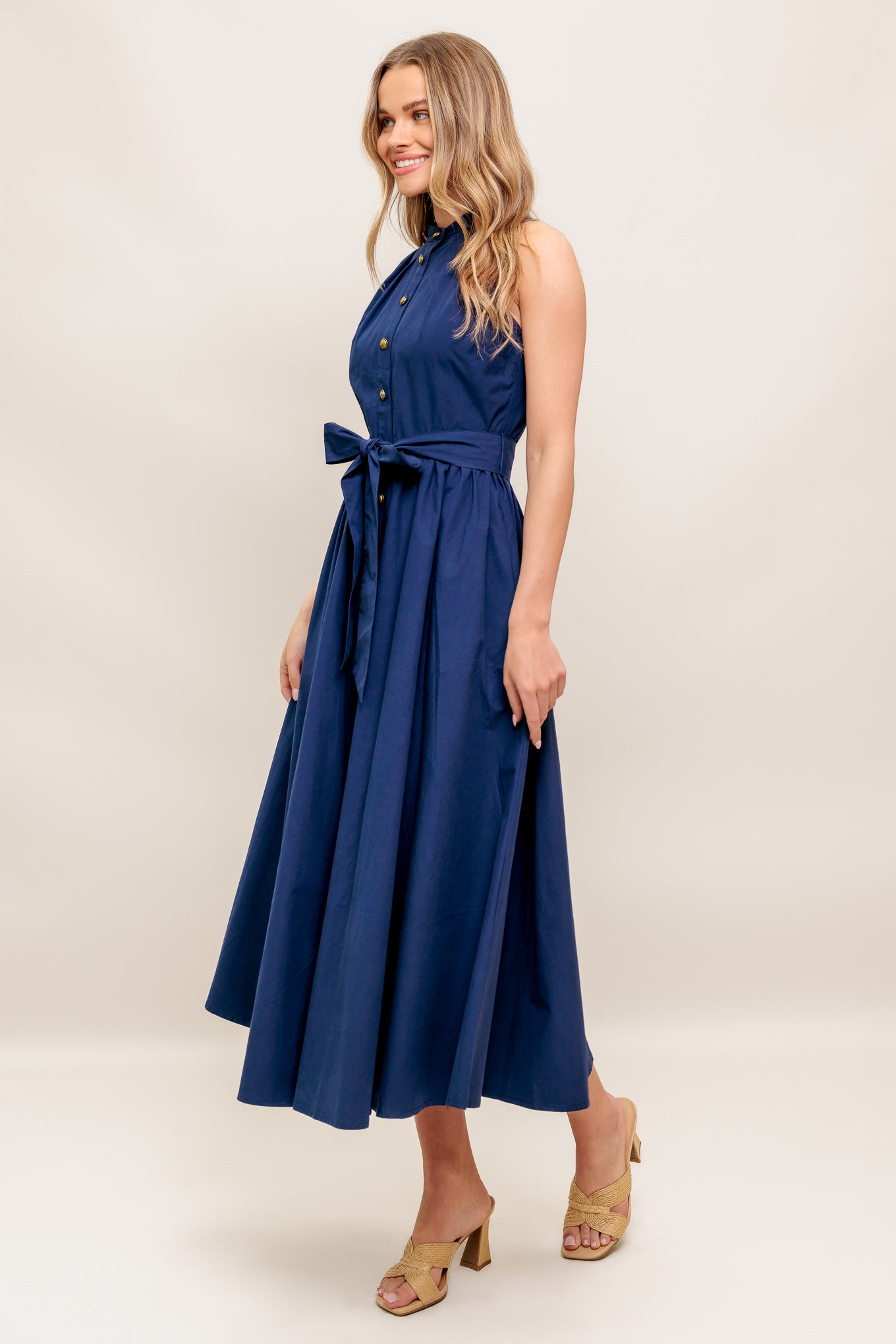 A solid navy woven midi dress featuring high neckline, sleeveless, button down, self sash tie and full skirt