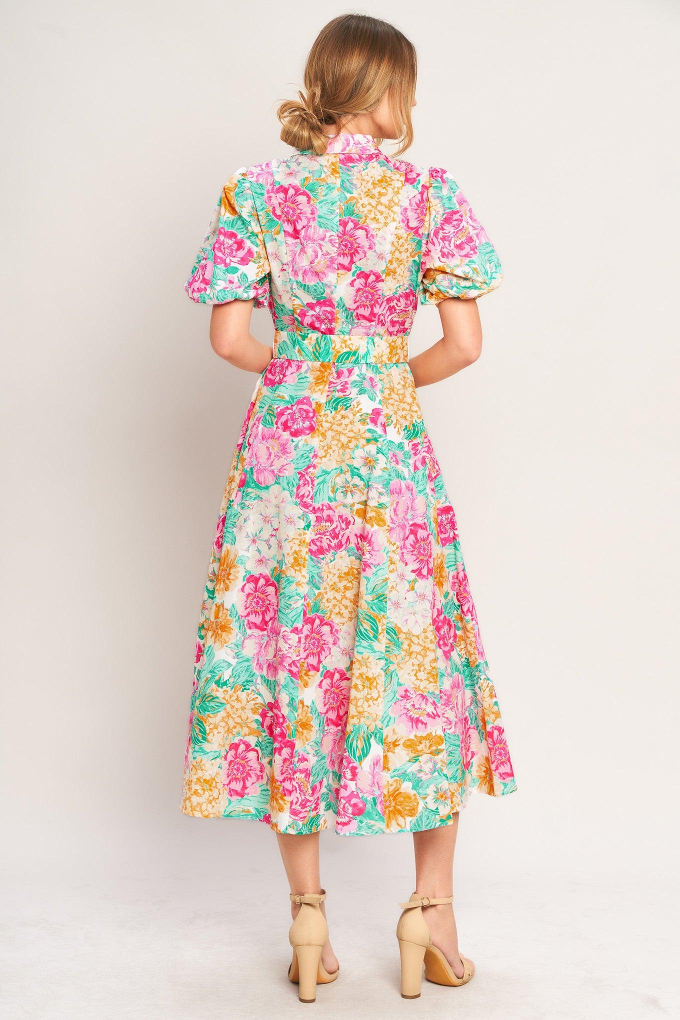 Woman wearing a colorful floral dress against a plain background
