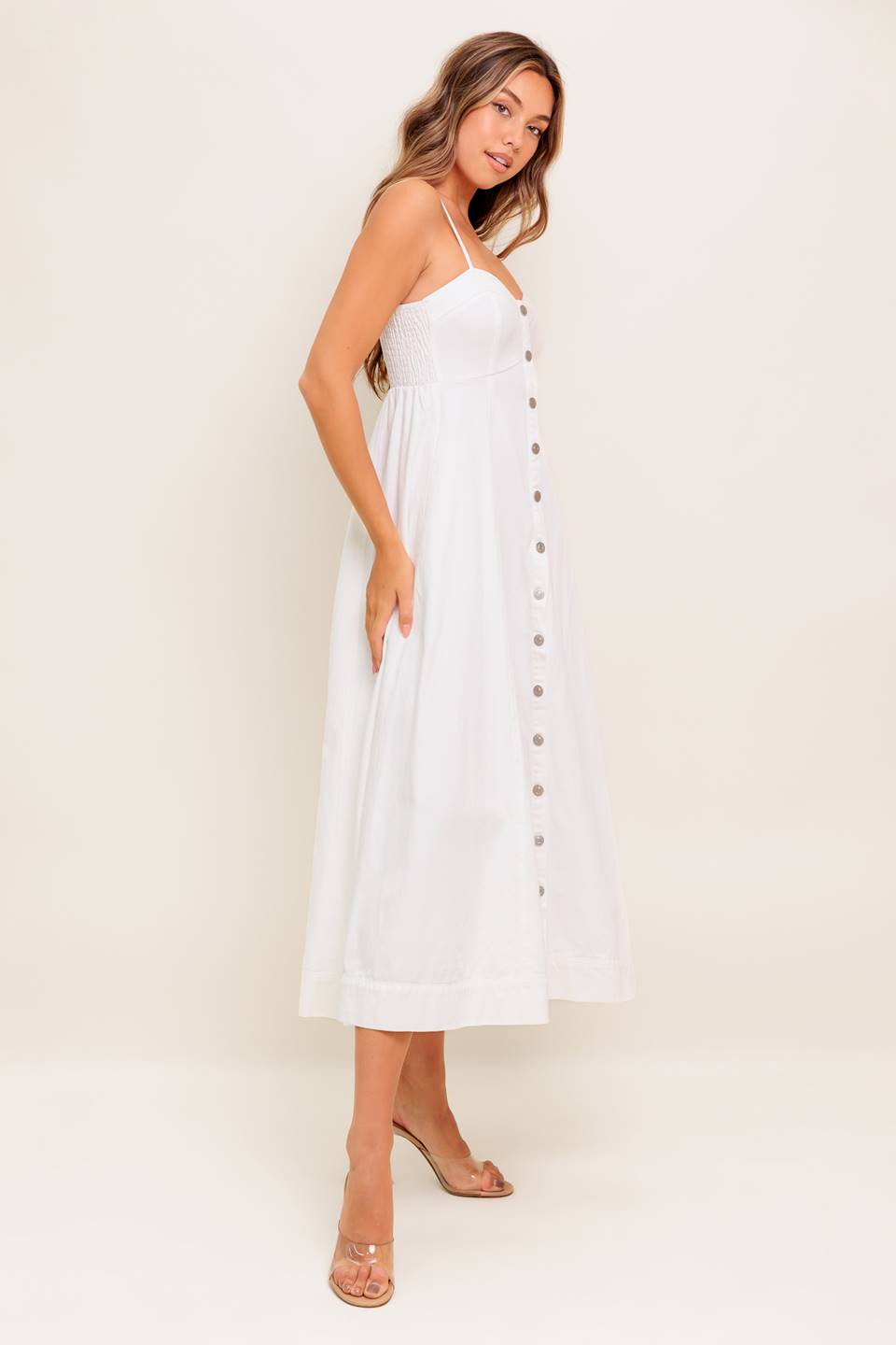 A solid woven midi dress featuring cami top, straps, front button down, full skirt and smocked back bodice