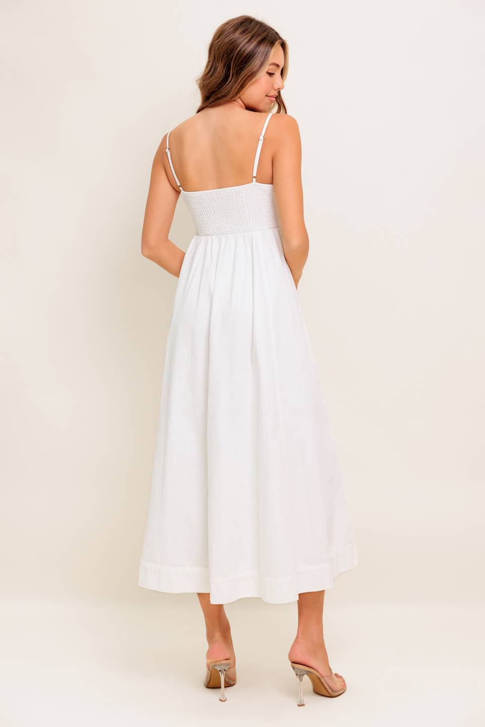 A solid woven midi dress featuring cami top, straps, front button down, full skirt and smocked back bodice