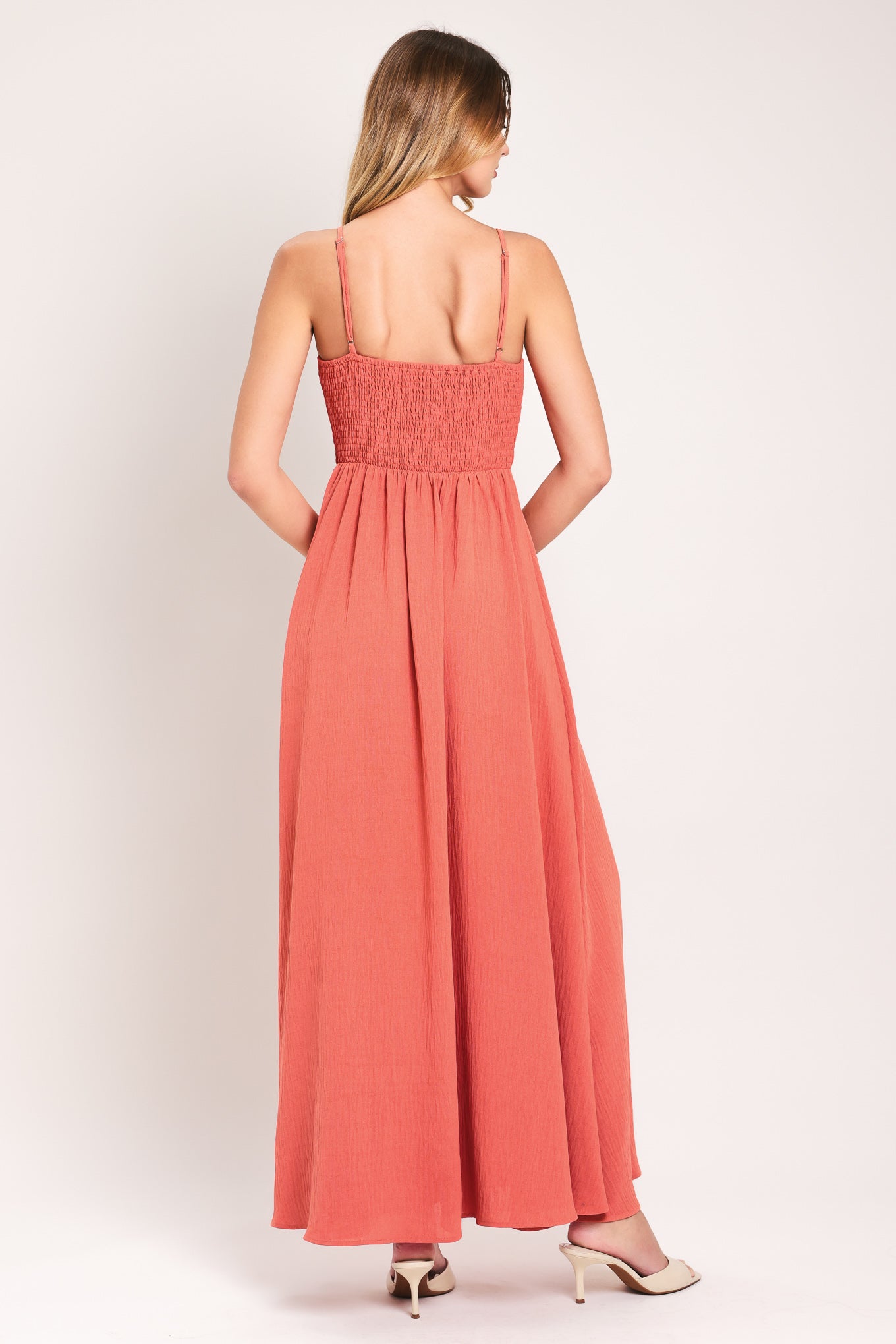 Woman wearing a coral maxi dress featuring cami top, waist yoke with shirring and button, elastic waist and smocked back bodice | Flying Tomato