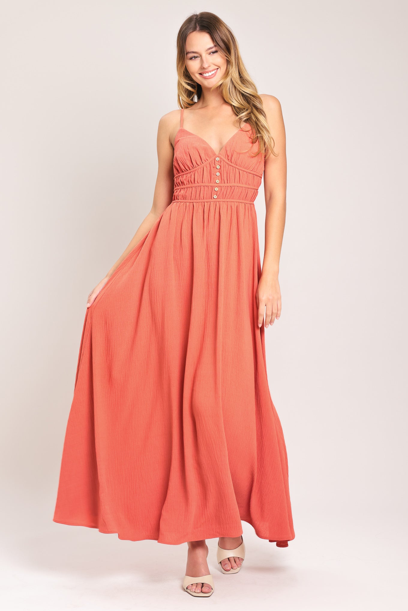 Woman wearing a coral maxi dress featuring cami top, waist yoke with shirring and button, elastic waist and smocked back bodice | Flying Tomato
