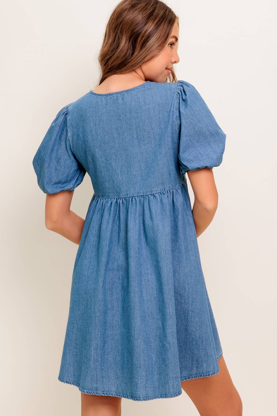 A washed denim mini dress featuring round neckline, front bow ties and short puff sleeve