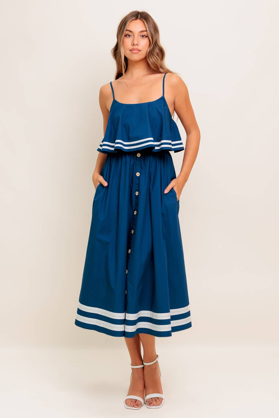 A solid navy woven midi dress featuring U neckline, straps, pop over, and button down skirt