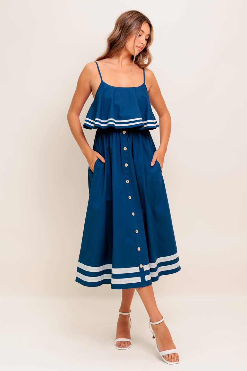 A solid navy woven midi dress featuring U neckline, straps, pop over, and button down skirt
