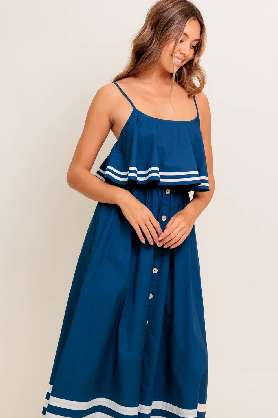 A solid navy woven midi dress featuring U neckline, straps, pop over, and button down skirt