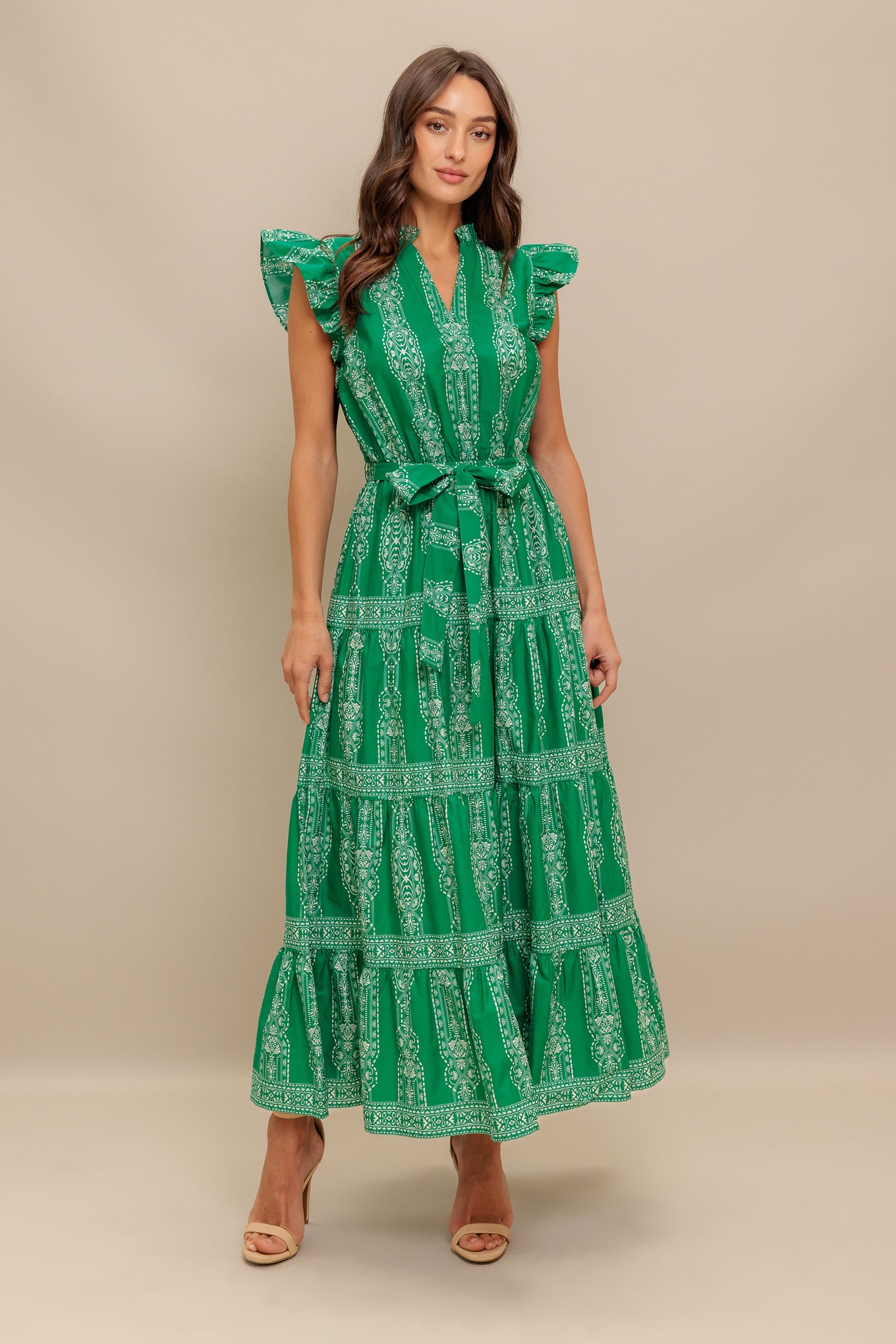 A printed woven midi dress featuring ruffled neckline with V center, short ruffle sleeve, elasticized waist with self sash tie and tiered skirt