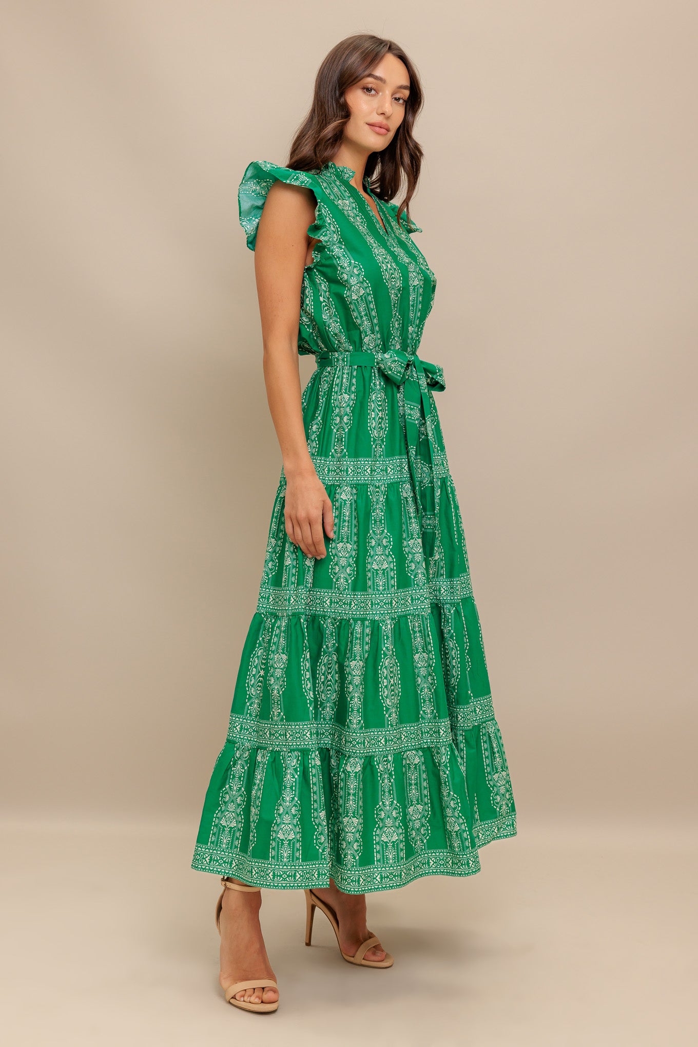 A printed woven midi dress featuring ruffled neckline with V center, short ruffle sleeve, elasticized waist with self sash tie and tiered skirt