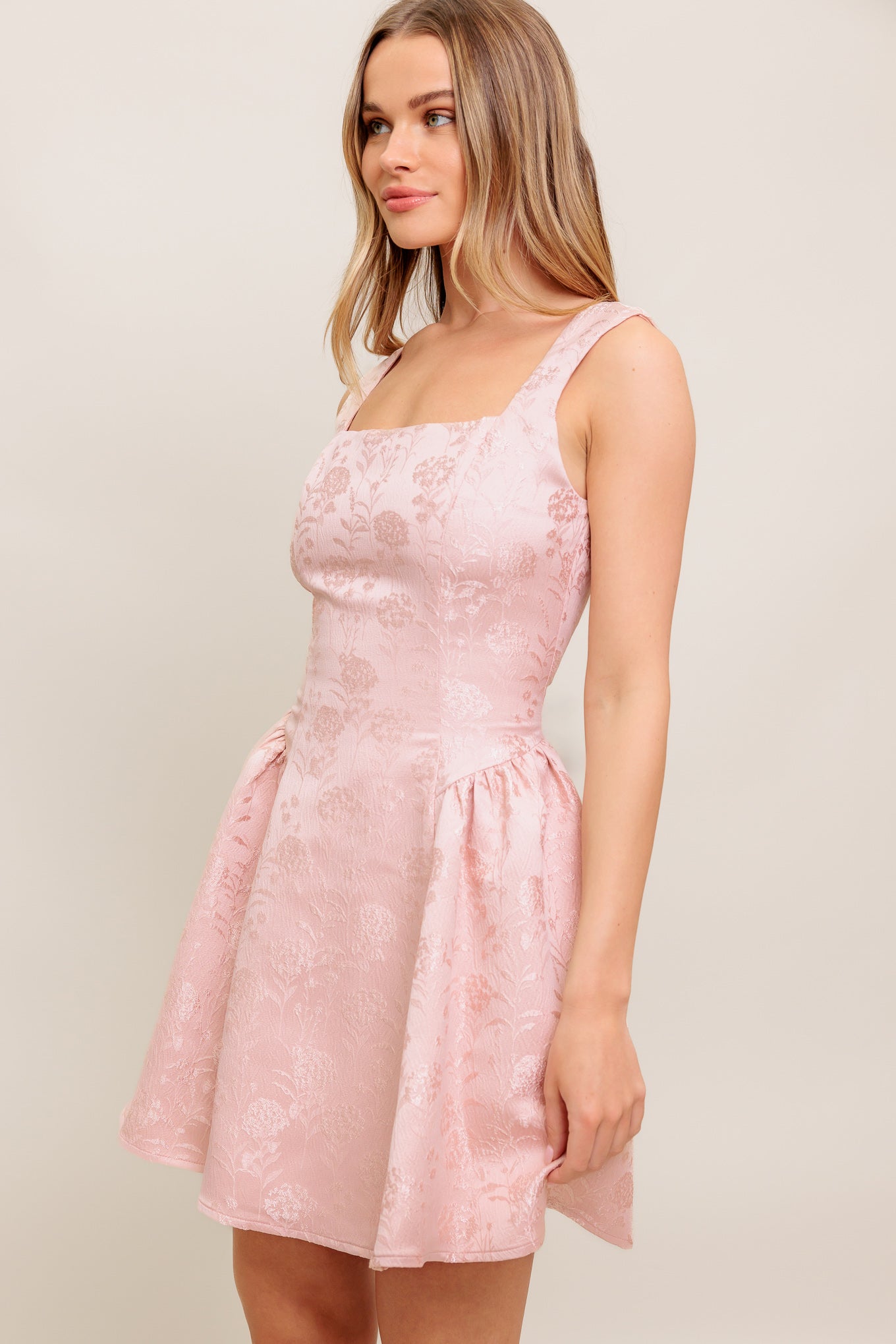 A woven jacquard satin mini dress featuring square neckline, sleeveless, side shirring and back zipper closure