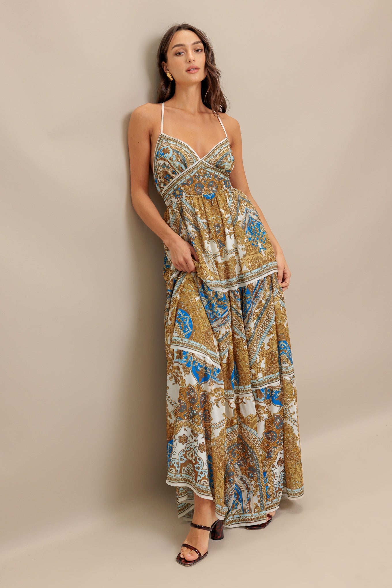 A printed woven maxi dress featuring cami bodice, straps, waist yoke, tiered skirt, open back with ties and smocked back waistband