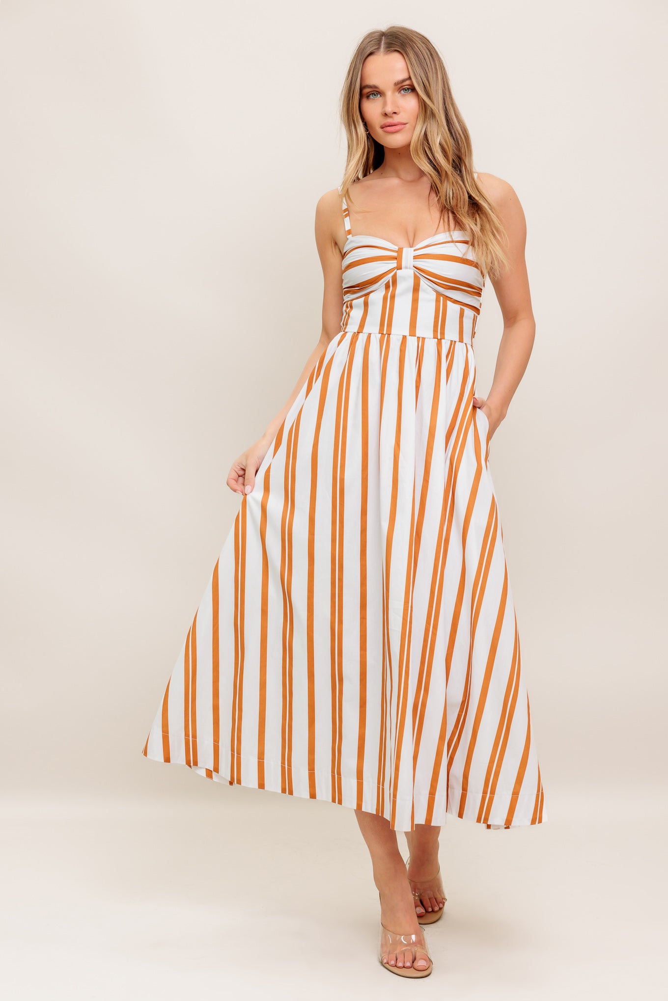 A striped woven midi dress featuring sweetheart neckline with shirred cup, straps, full skirt and smocked back bodice