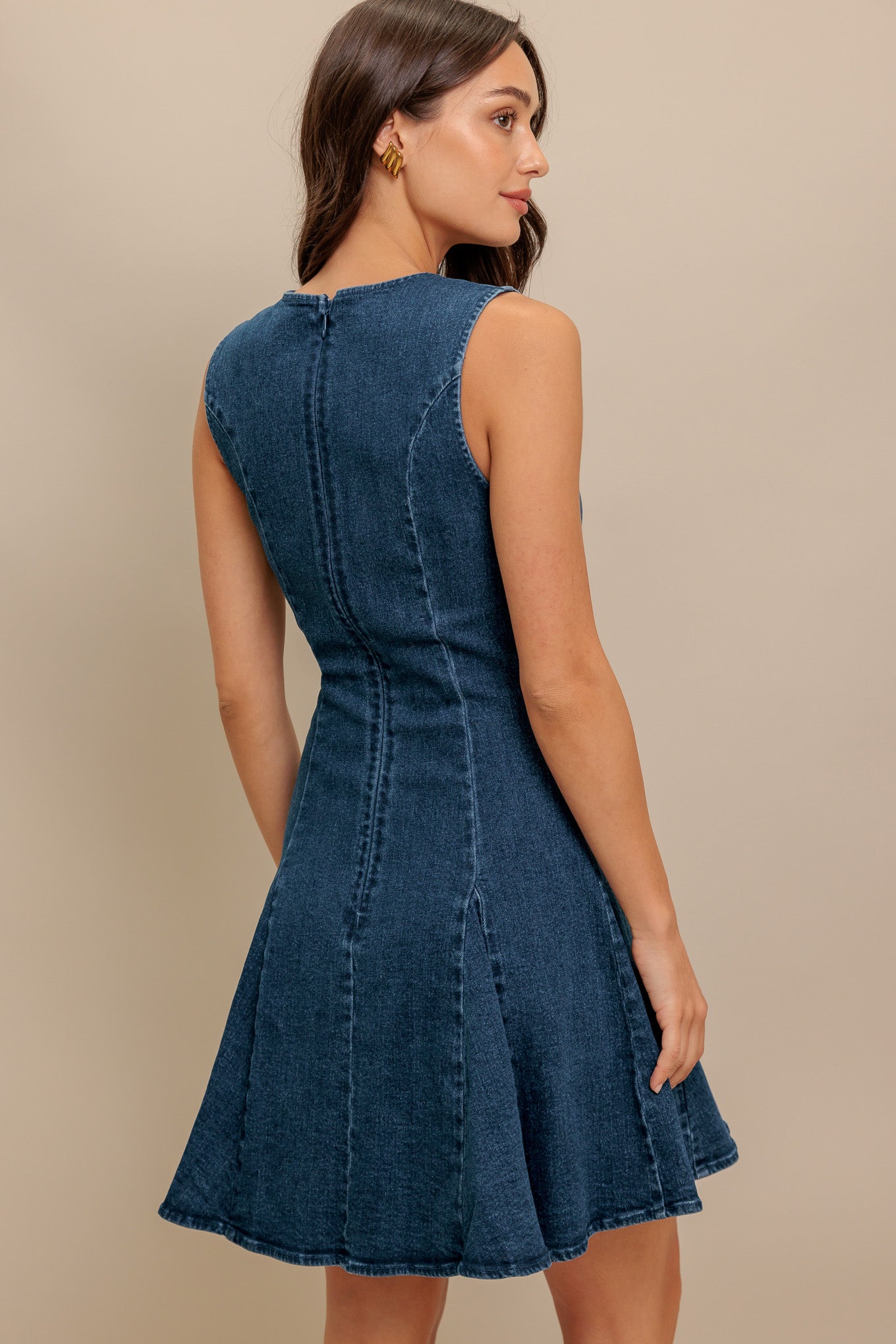 A washed denim mini dress featuring round neckline, sleeveless, front bow ties, circle skirt and back zipper closure
