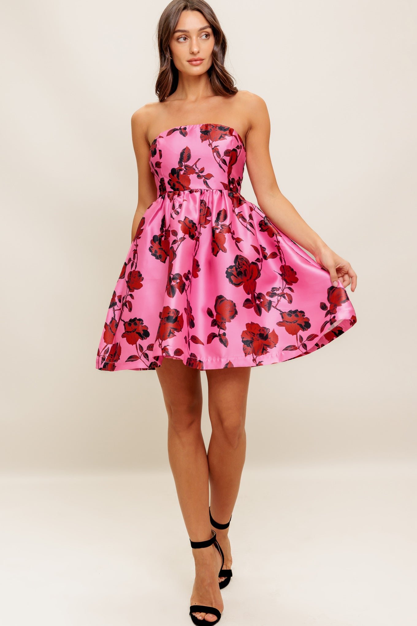 This strapless mini dress showcases a pink floral pattern on woven fabric, designed with a full skirt and secured by a back zipper closure.