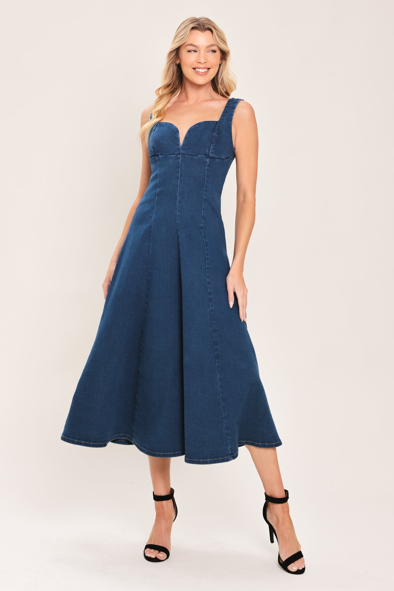 Woman wearing a sleeveless indigo denim midi dress featuring sweetheart neckline, circle skirt and back zipper closure | Flying Tomato