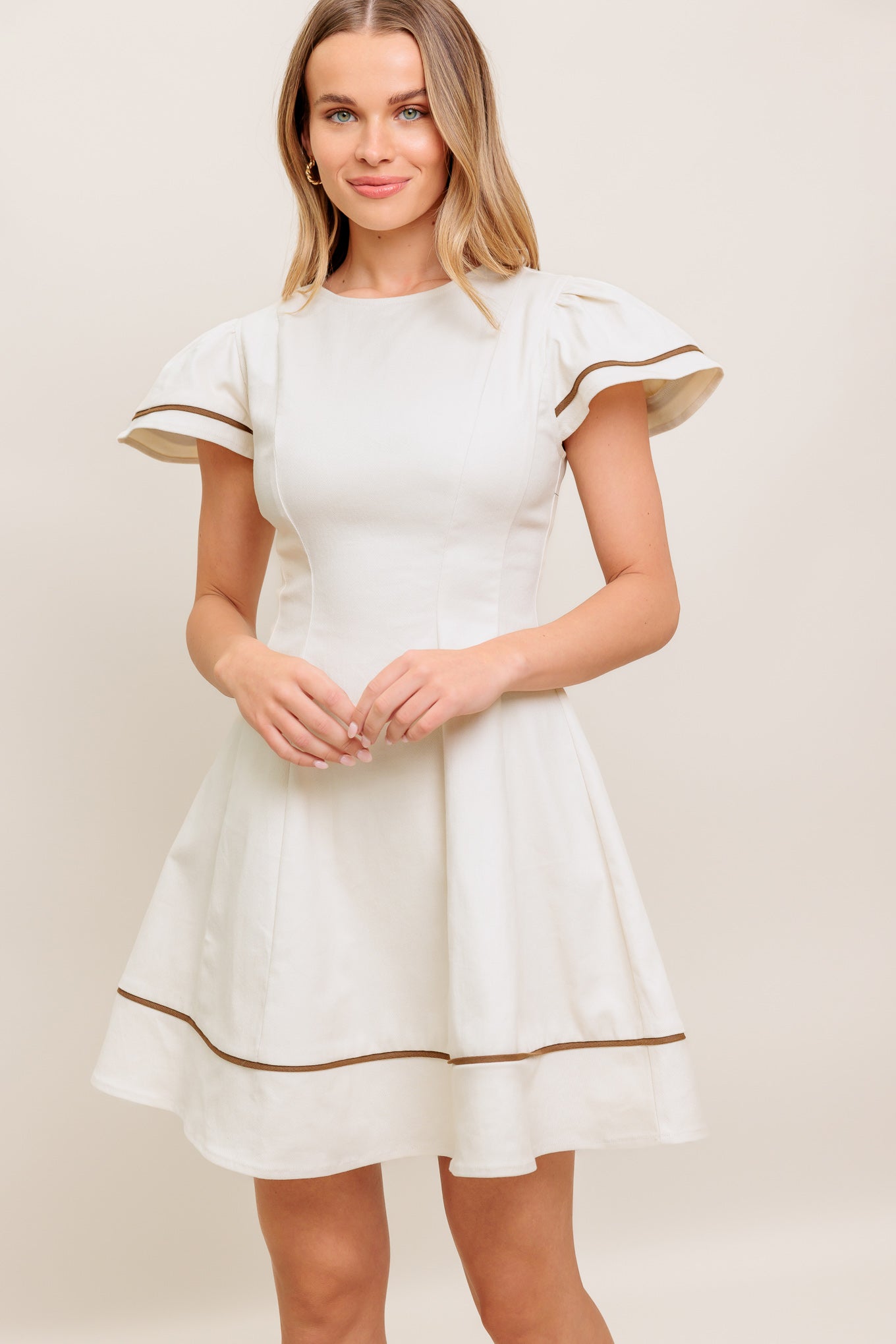 A solid woven mini dress featuring round neckline, short flutter sleeve, circle skirt and back zipper closure