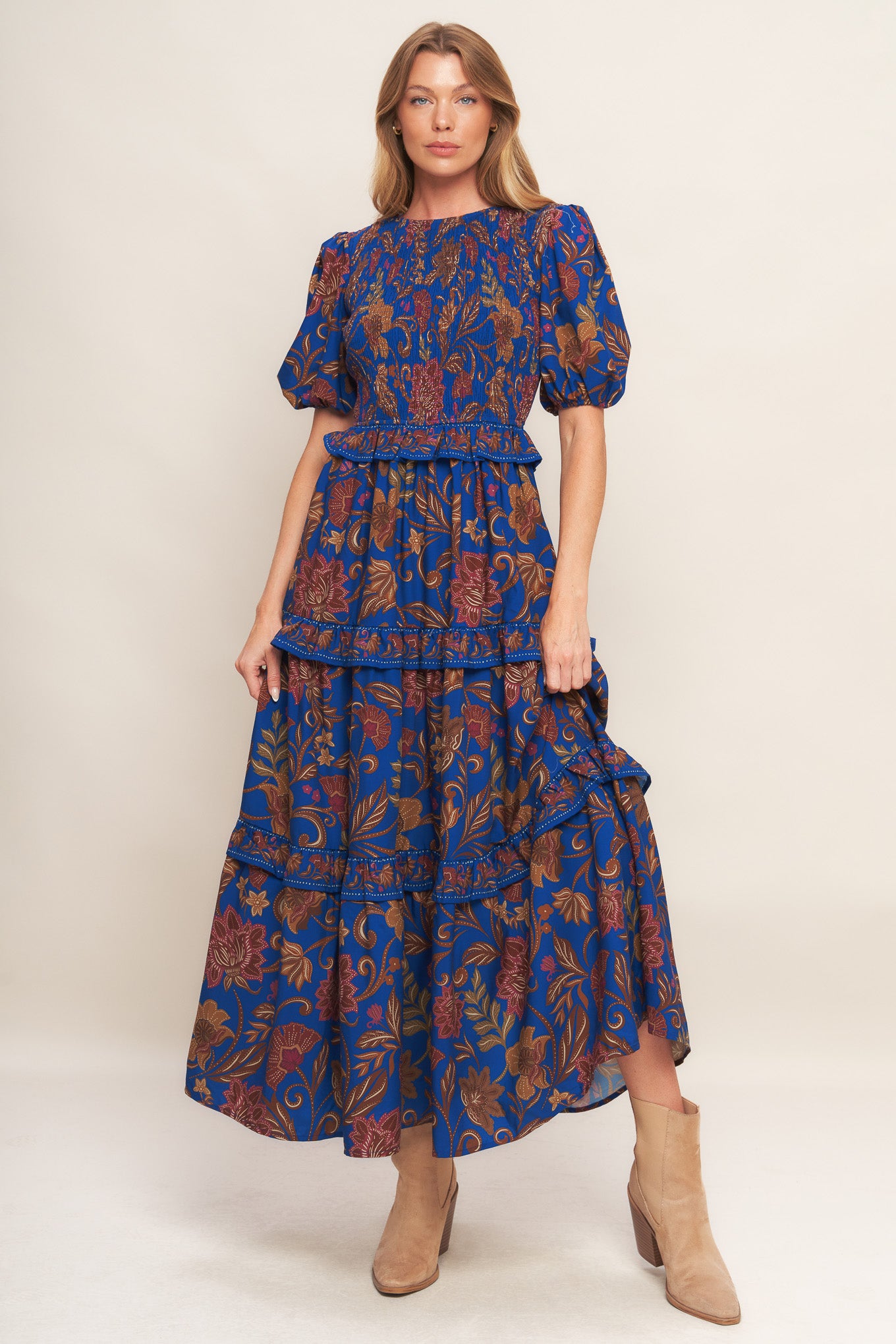 A printed woven midi dress featuring round neckline, smocked bodice, short puff sleeve, tiered skirt with ruffles and back neck button closure