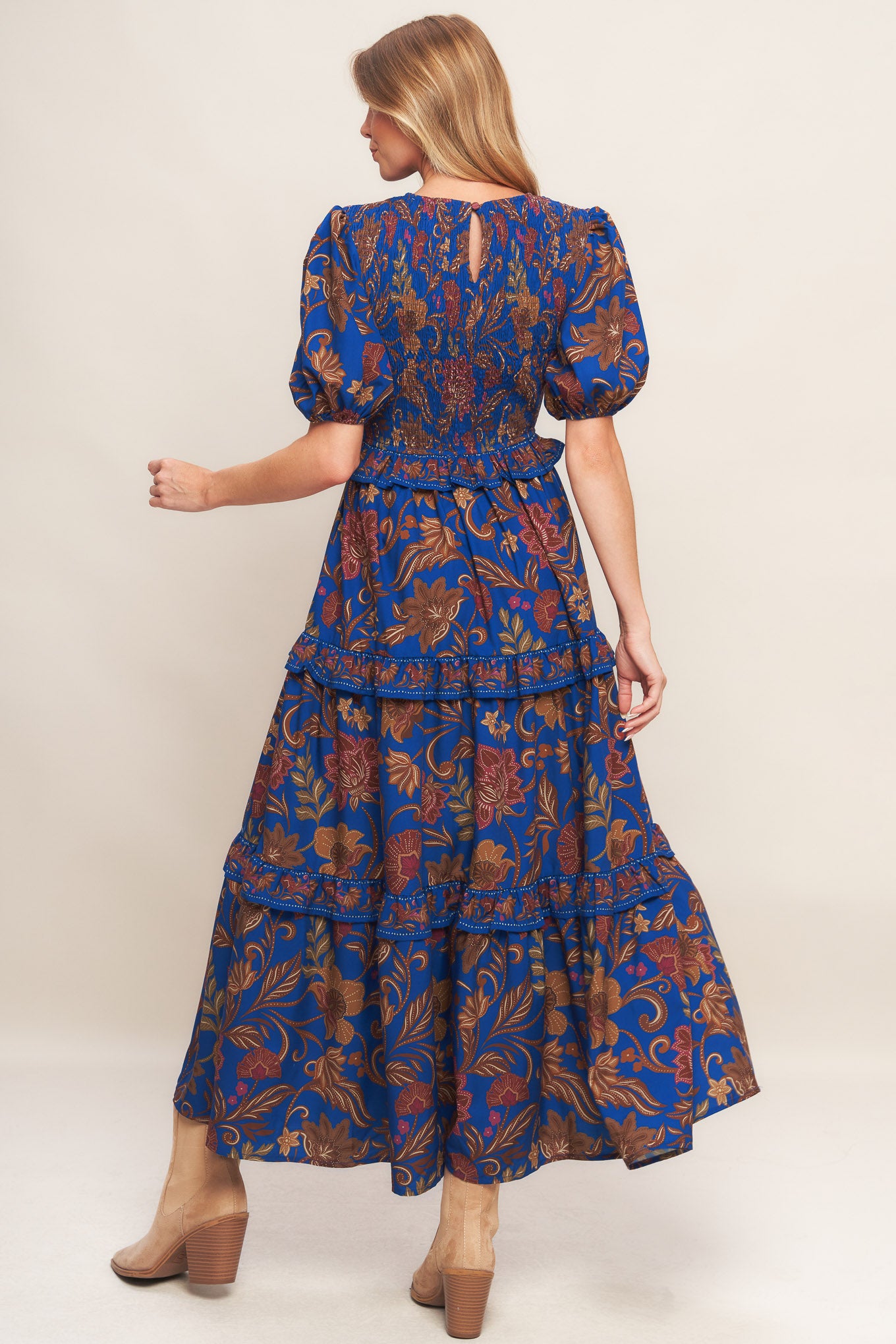 A printed woven midi dress featuring round neckline, smocked bodice, short puff sleeve, tiered skirt with ruffles and back neck button closure